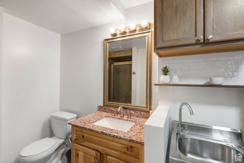 Bathroom with a tile shower, toilet, and vanity