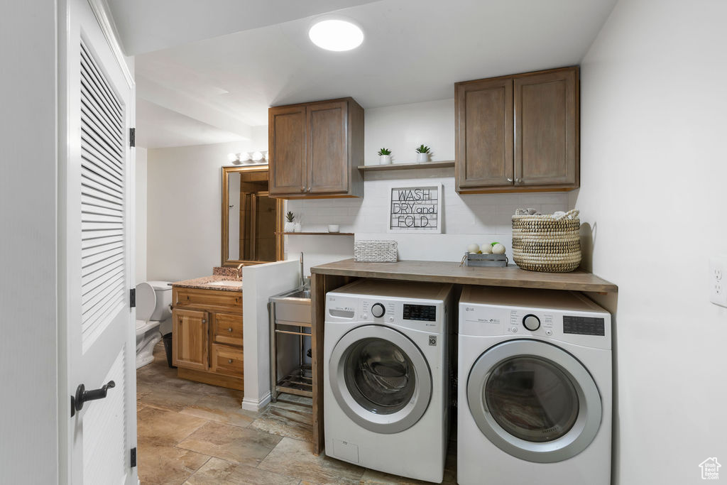 Laundry area with washer and clothes dryer, cabinet space, and stone finish flooring