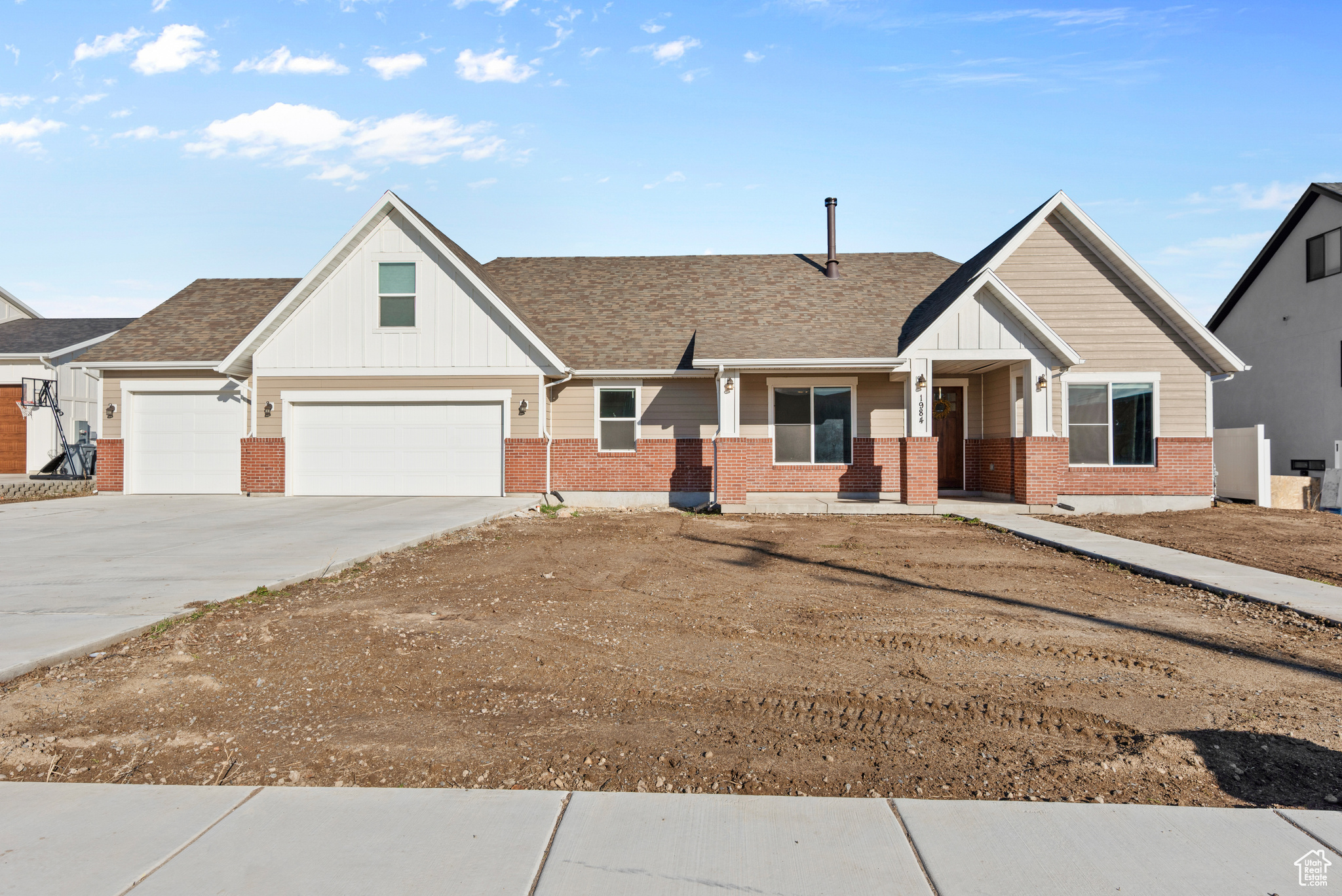 View of front of house with driveway, a shingled roof, board and batten siding, and brick siding