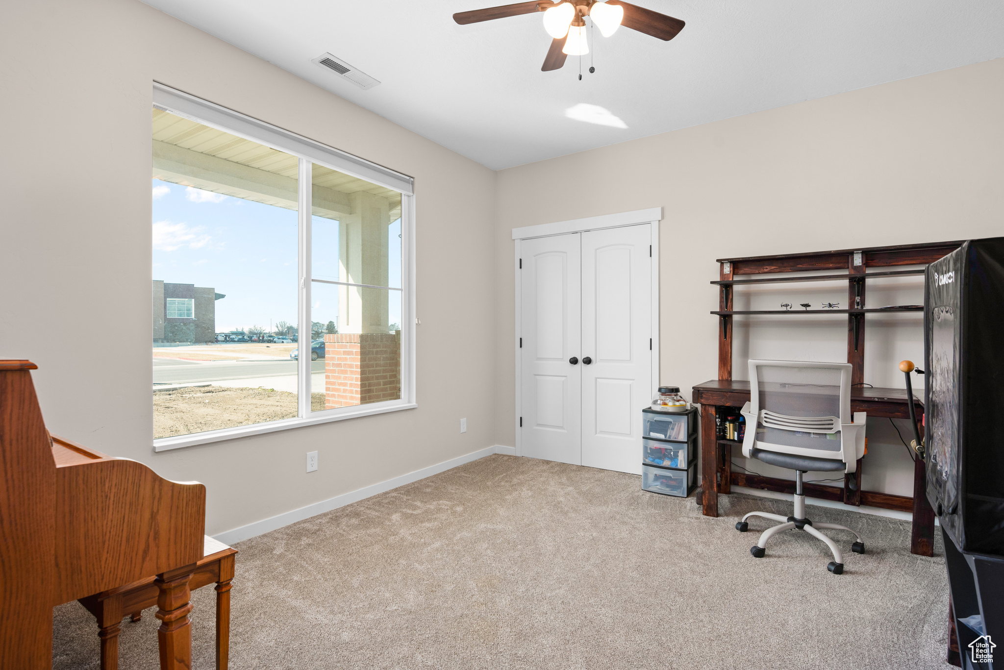 Home office with a ceiling fan, carpet flooring, visible vents, and baseboards