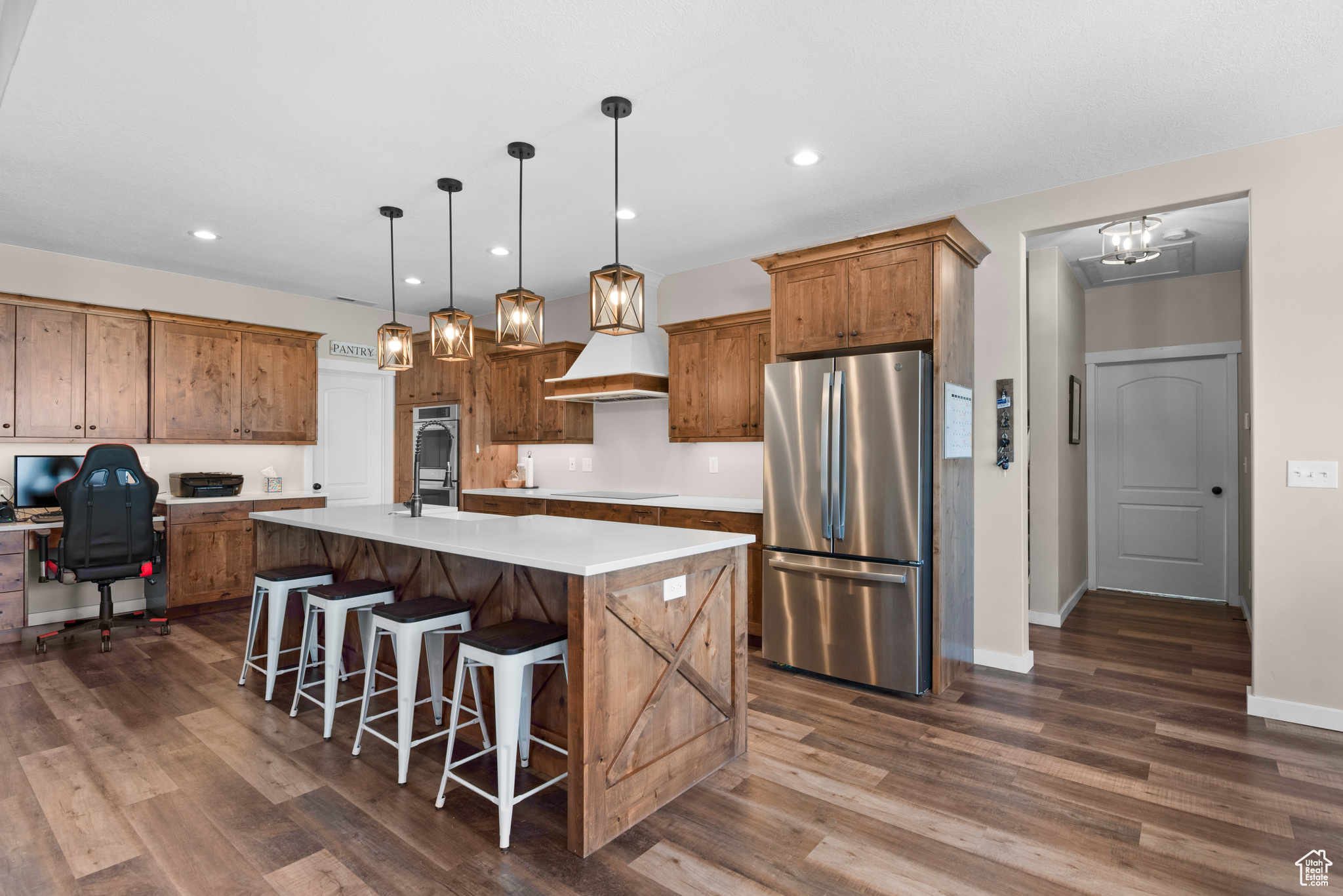 Kitchen featuring appliances with stainless steel finishes, a kitchen island with sink, dark wood-style flooring, and light countertops