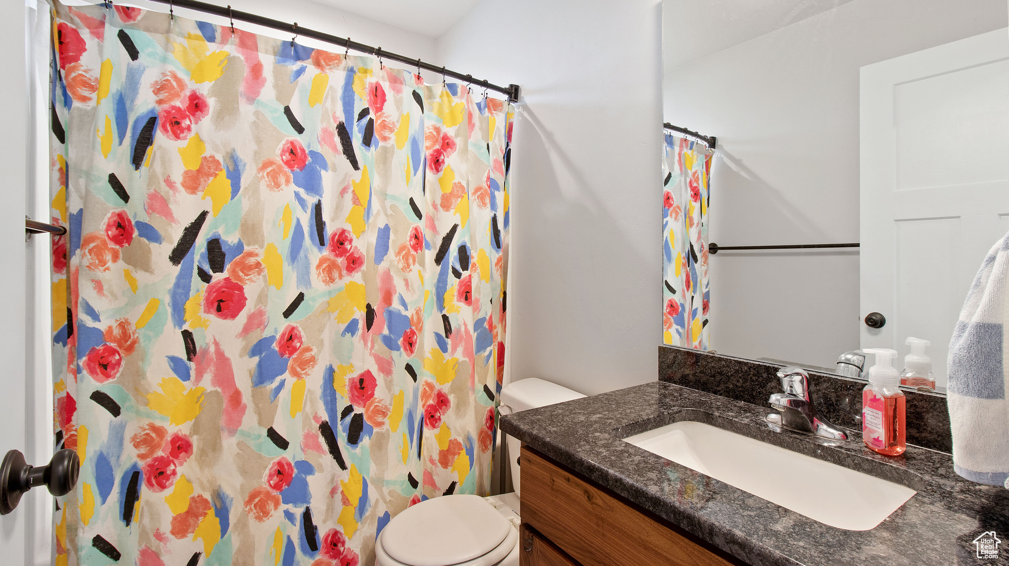 Bathroom featuring a shower with shower curtain, toilet, and vanity