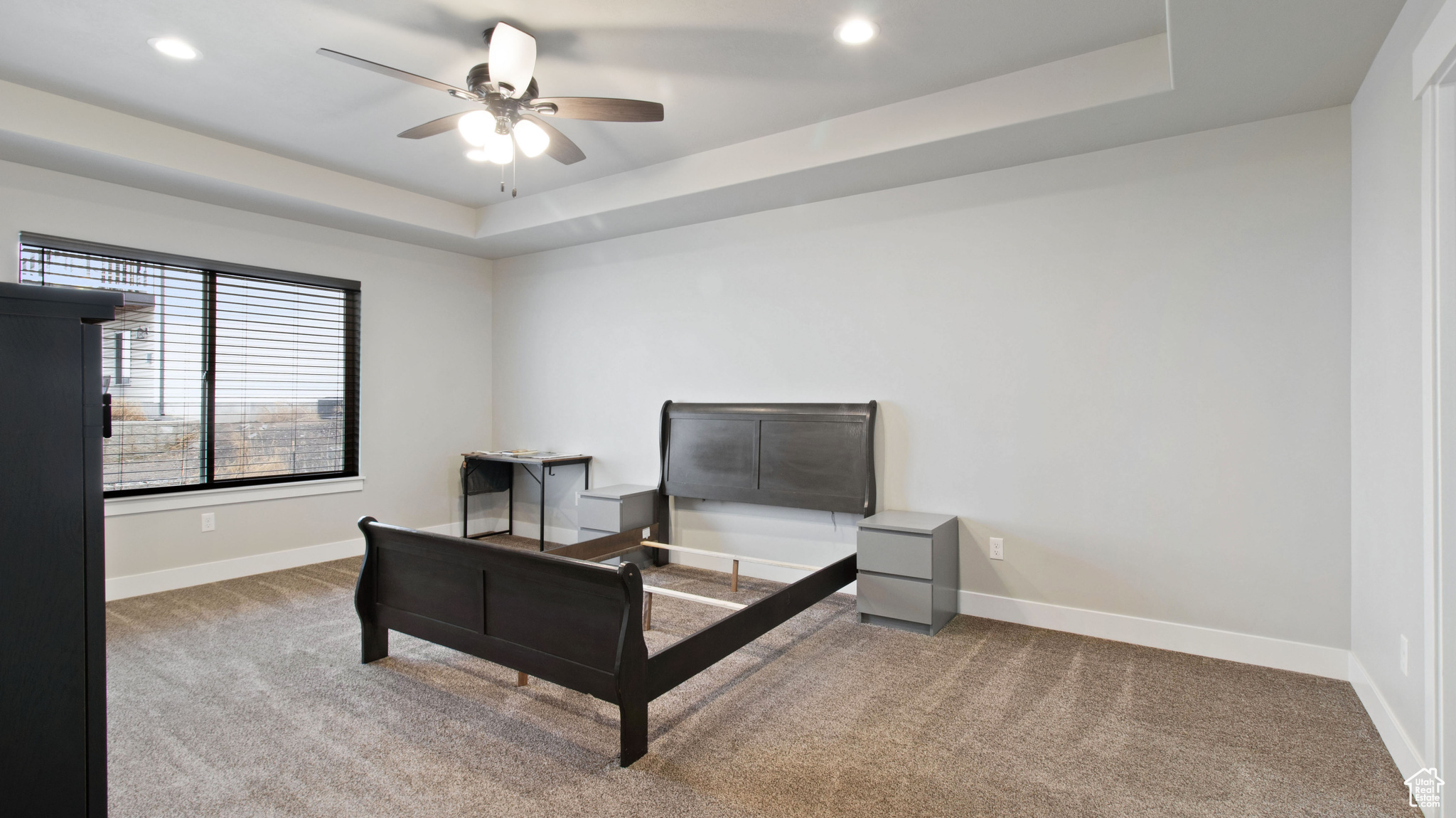 Carpeted bedroom with a raised ceiling, recessed lighting, and baseboards