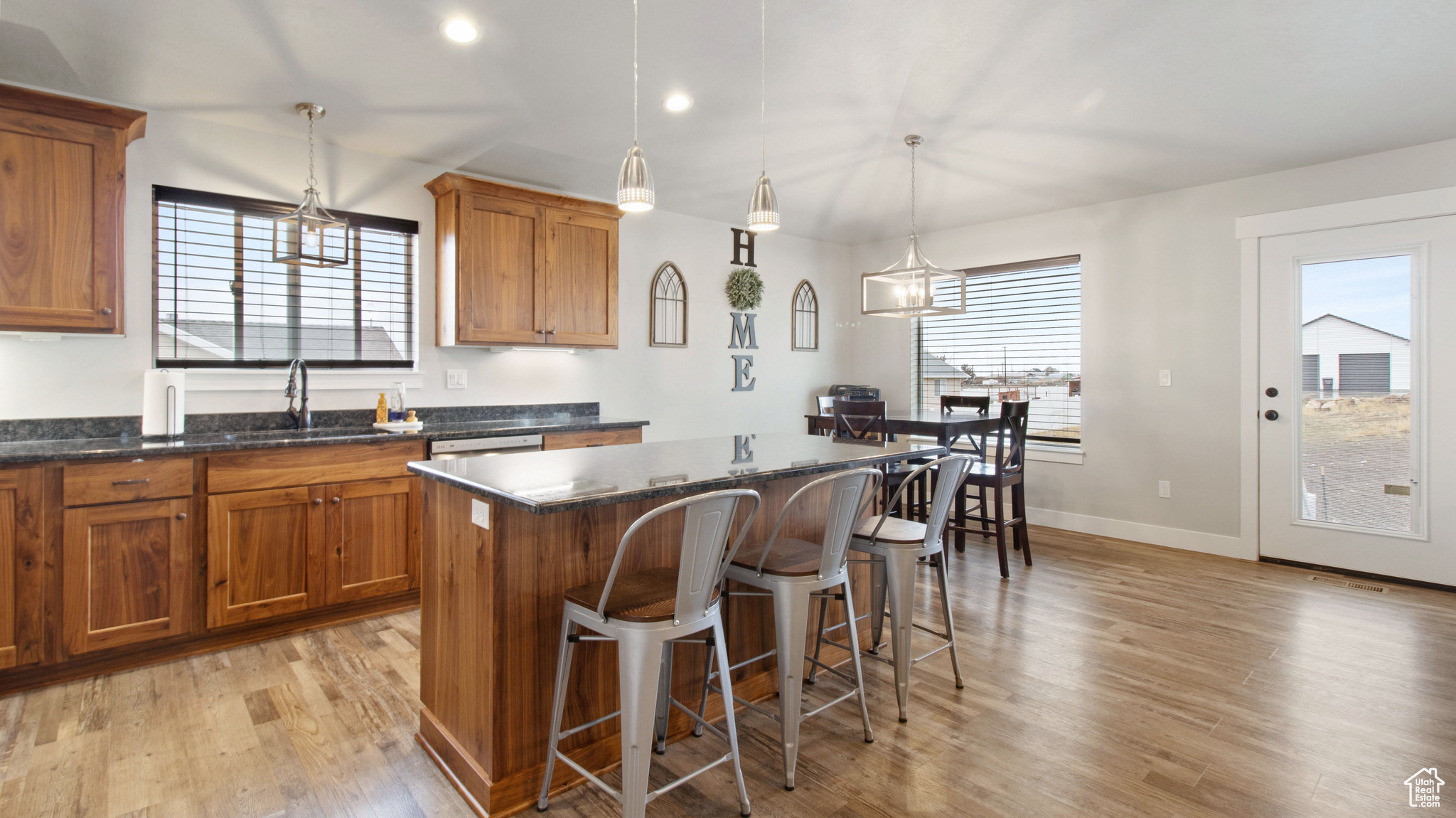 Kitchen featuring light wood-type flooring, brown cabinets, a kitchen bar, a sink, and a kitchen island