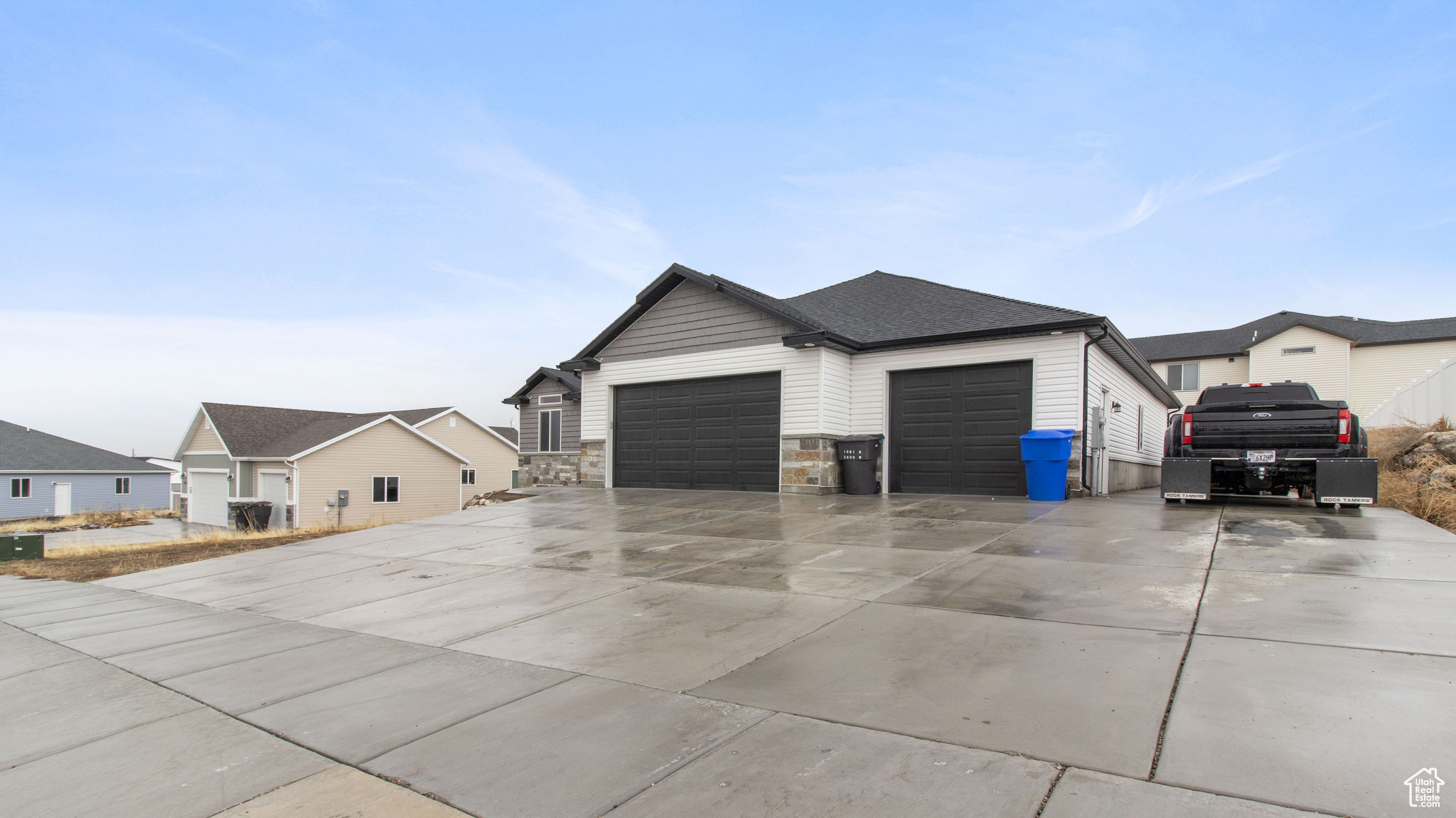 View of home's exterior with stone siding, driveway, a shingled roof, and a garage