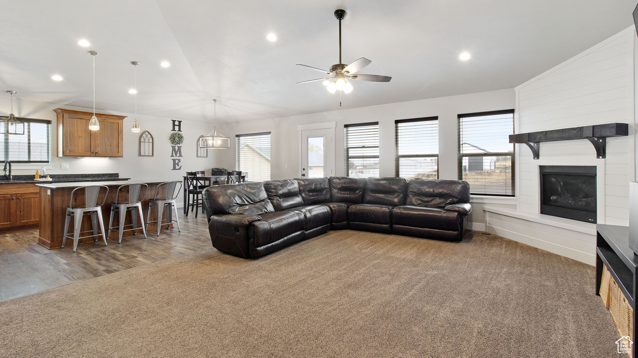 Carpeted living area with ceiling fan, lofted ceiling, recessed lighting, a fireplace, and wood finished floors