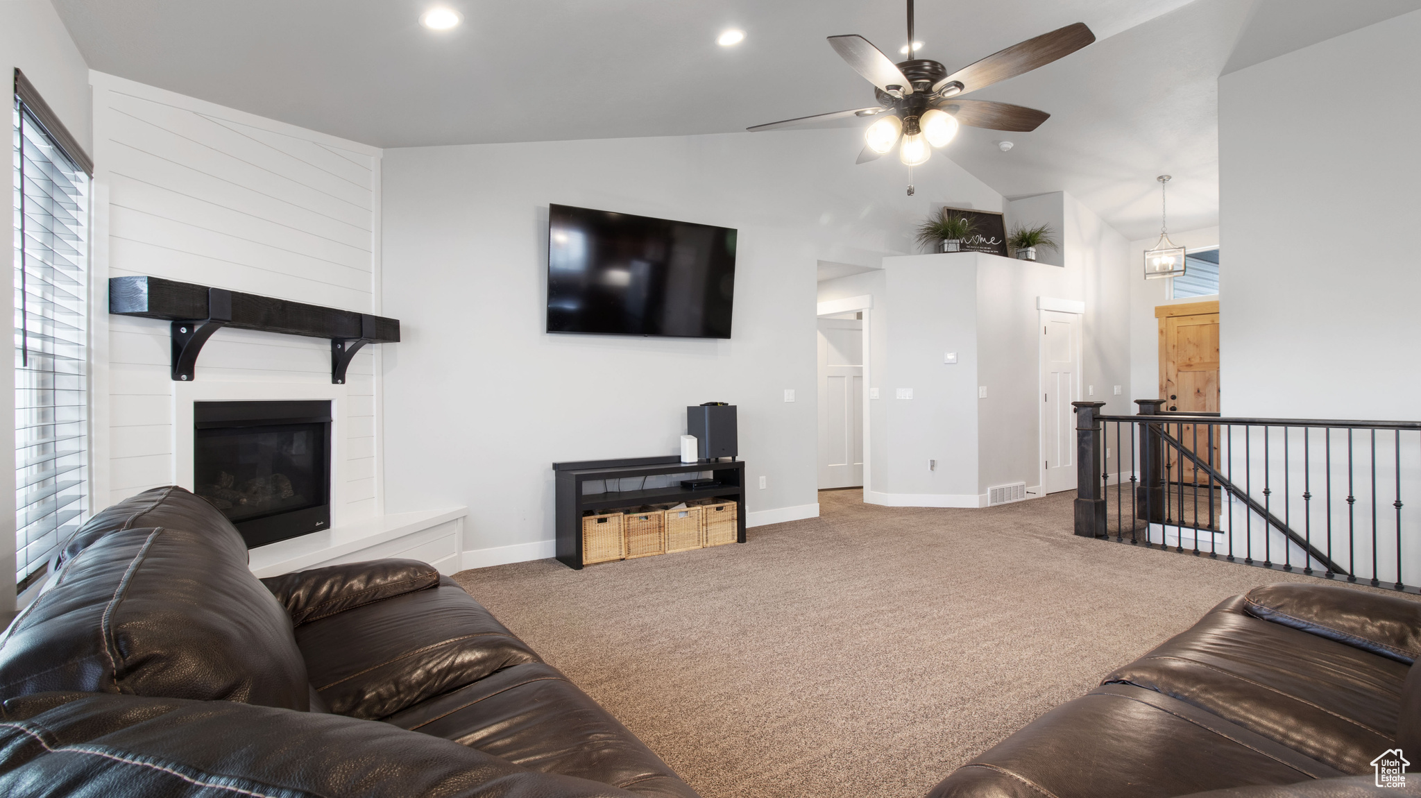 Carpeted living area with a large fireplace, baseboards, vaulted ceiling, recessed lighting, and a ceiling fan