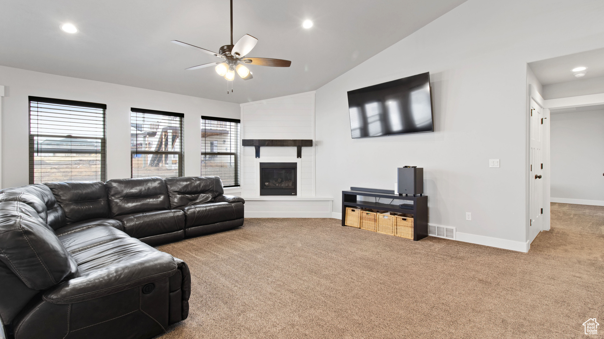 Living area featuring visible vents, a large fireplace, vaulted ceiling, carpet floors, and recessed lighting