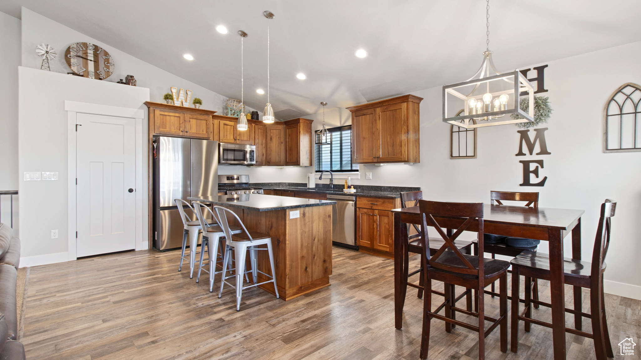 Kitchen with a center island, light wood-type flooring, stainless steel appliances, and dark countertops