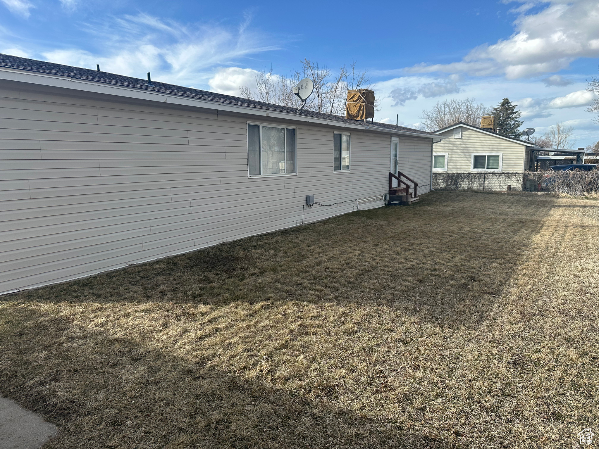 Back of house featuring a lawn, entry steps, and fence