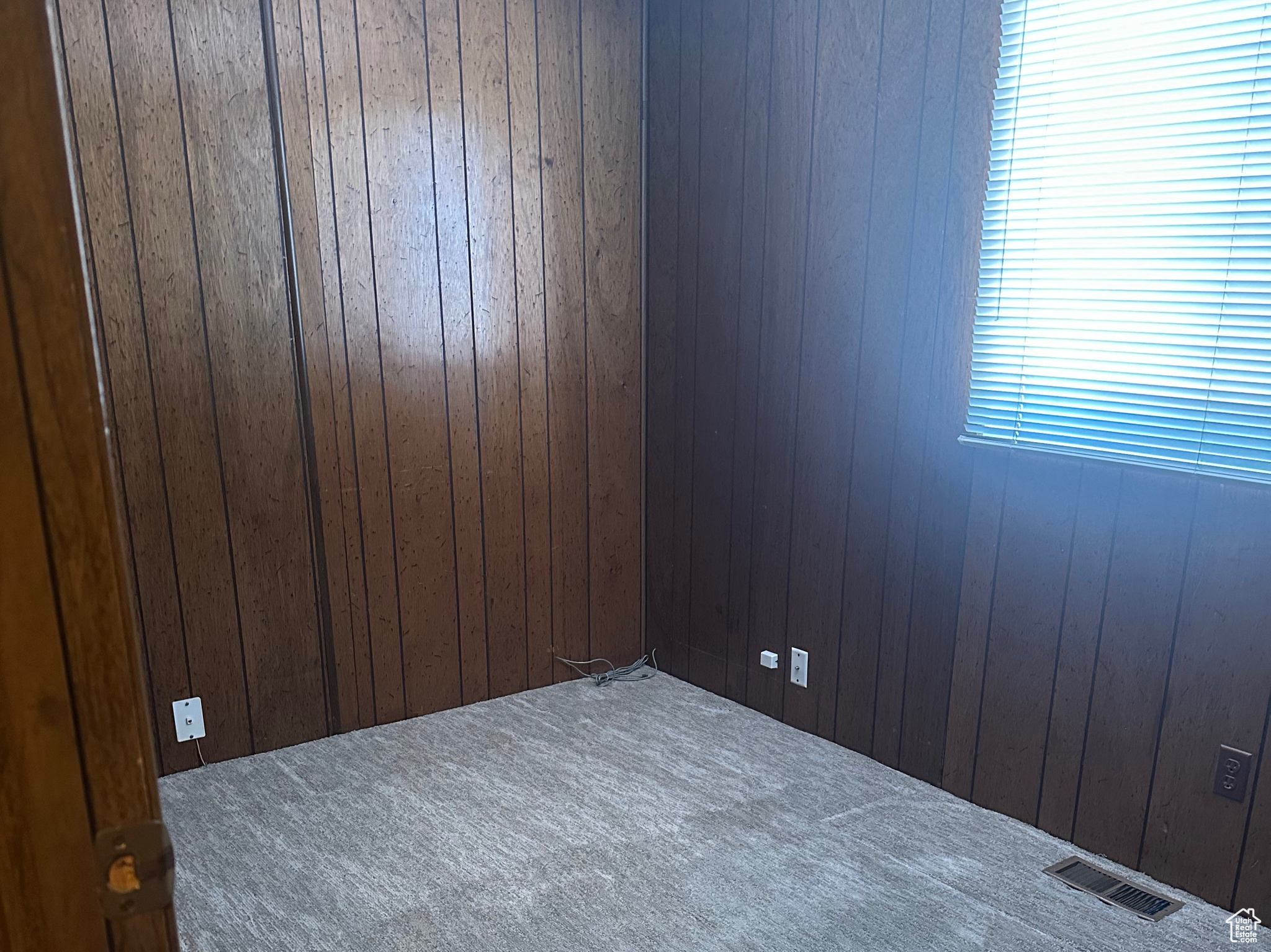 Carpeted empty room with visible vents and wood walls