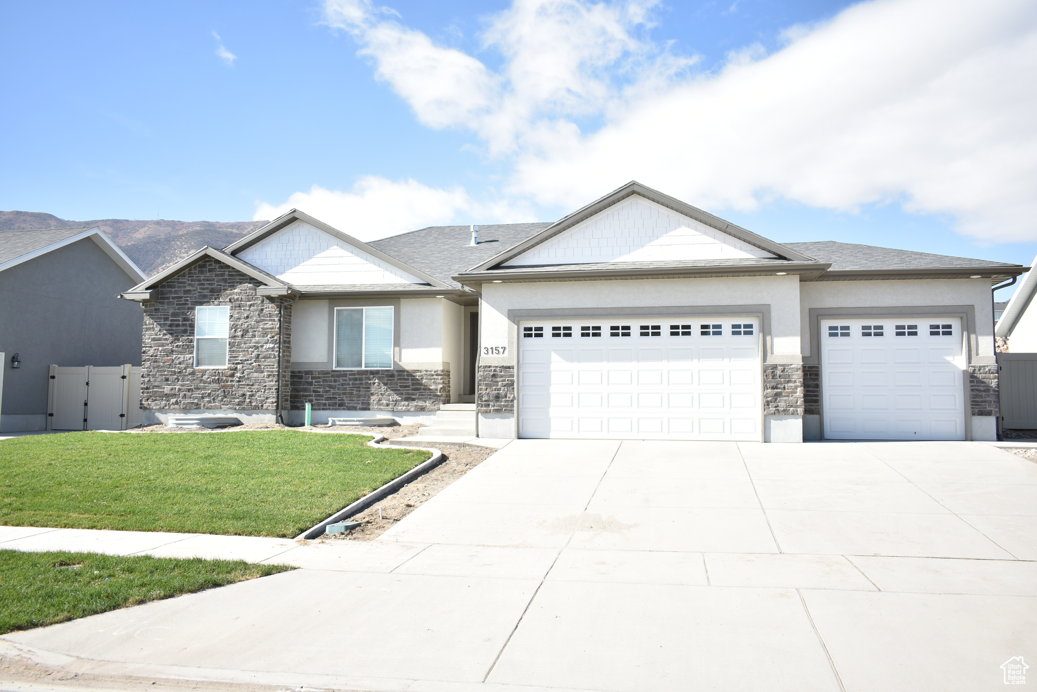 View of front facade with stone siding, concrete driveway, a front yard, and a garage