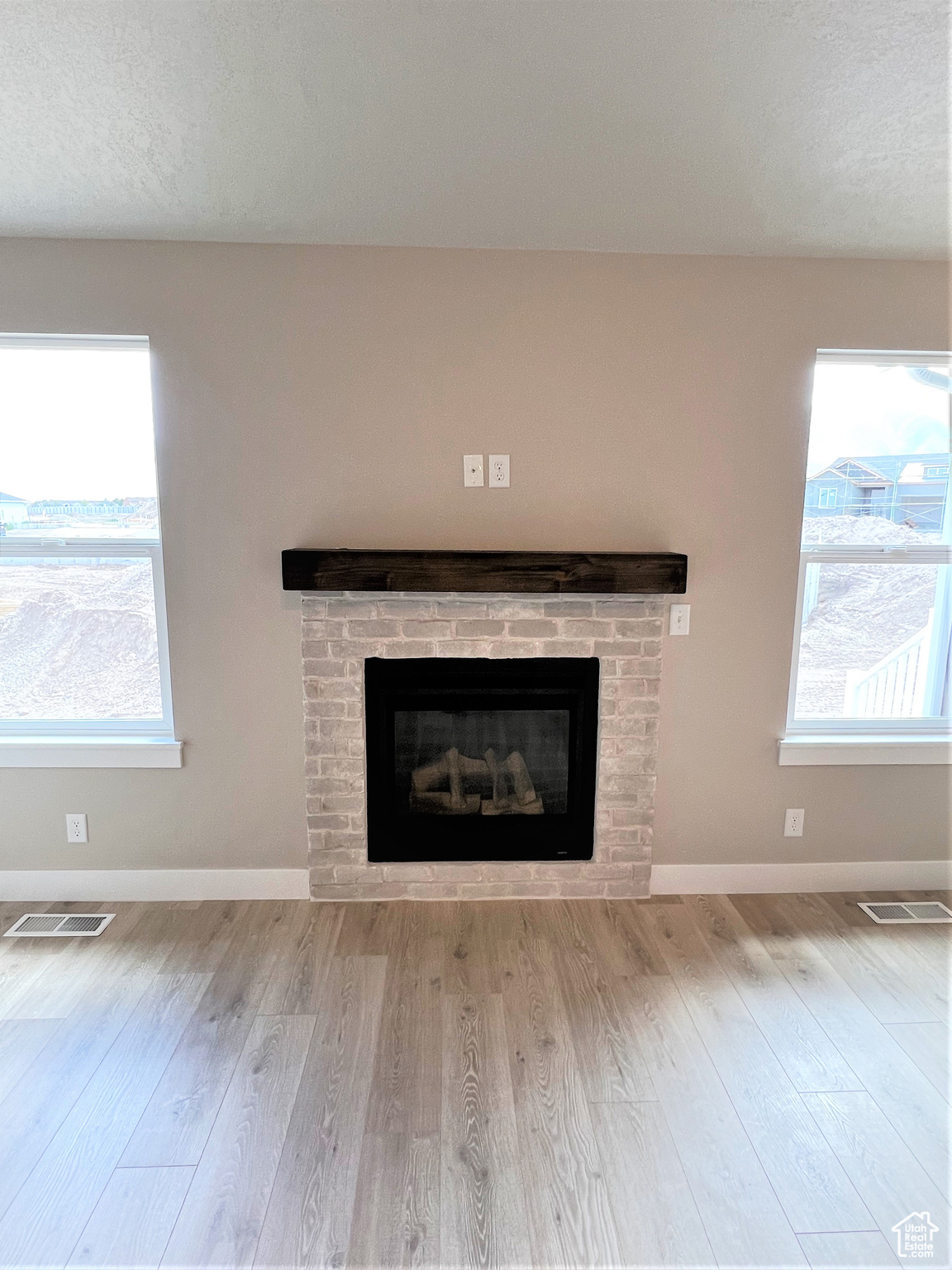 Details featuring visible vents, a brick fireplace, baseboards, and wood finished floors