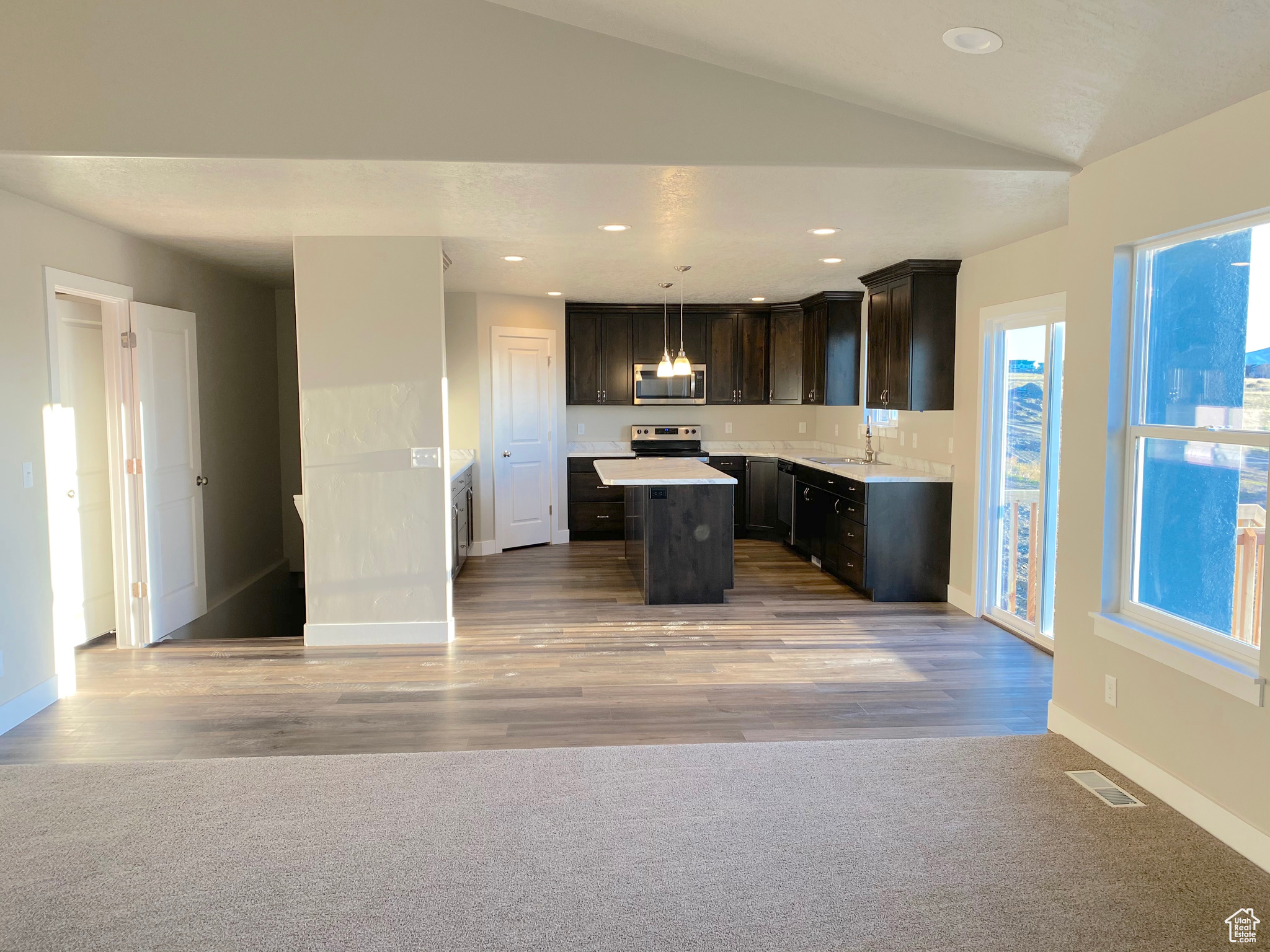 Kitchen with visible vents, a center island, vaulted ceiling, appliances with stainless steel finishes, and a sink