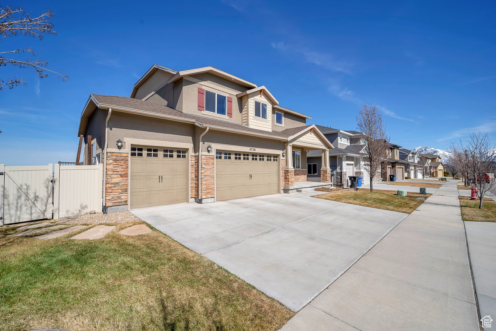 Craftsman house with a gate, driveway, stucco siding, stone siding, and a residential view