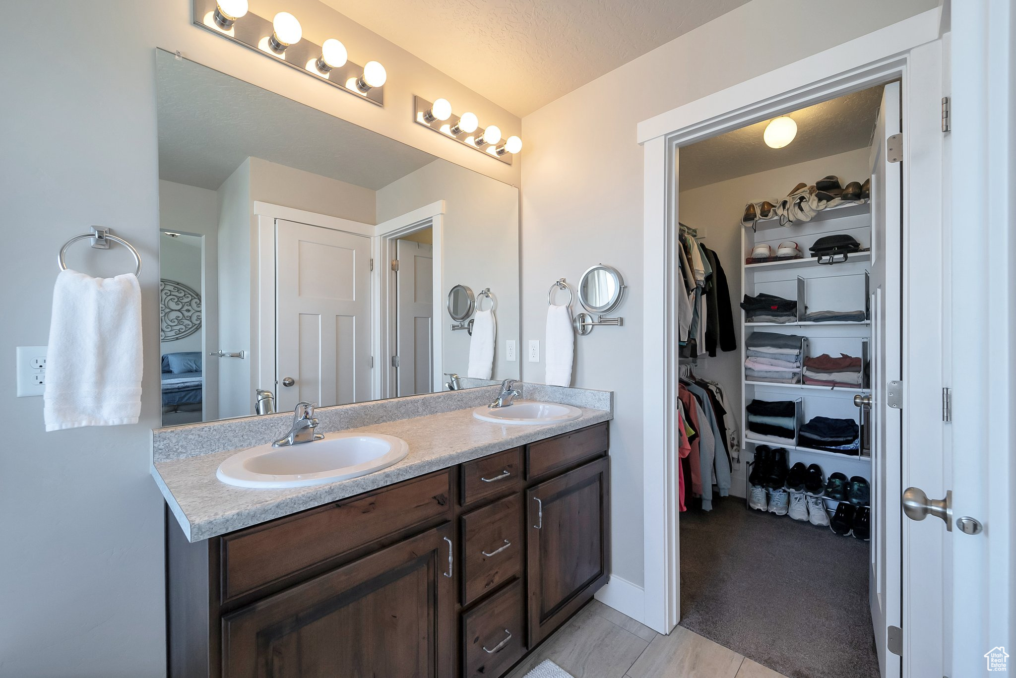 Full bathroom with a walk in closet, double vanity, and a sink