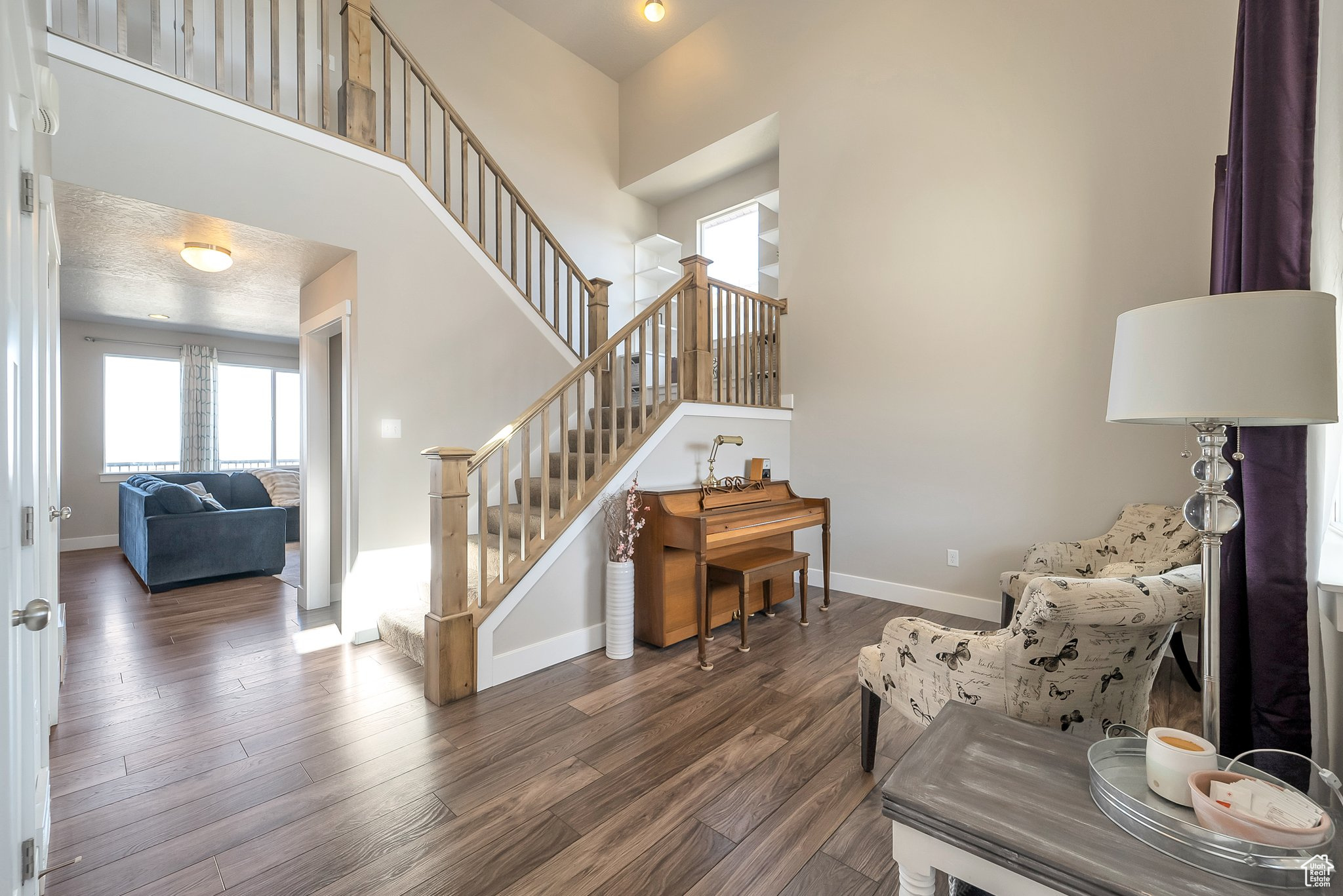 Living area featuring a high ceiling, stairway, wood finished floors, and baseboards