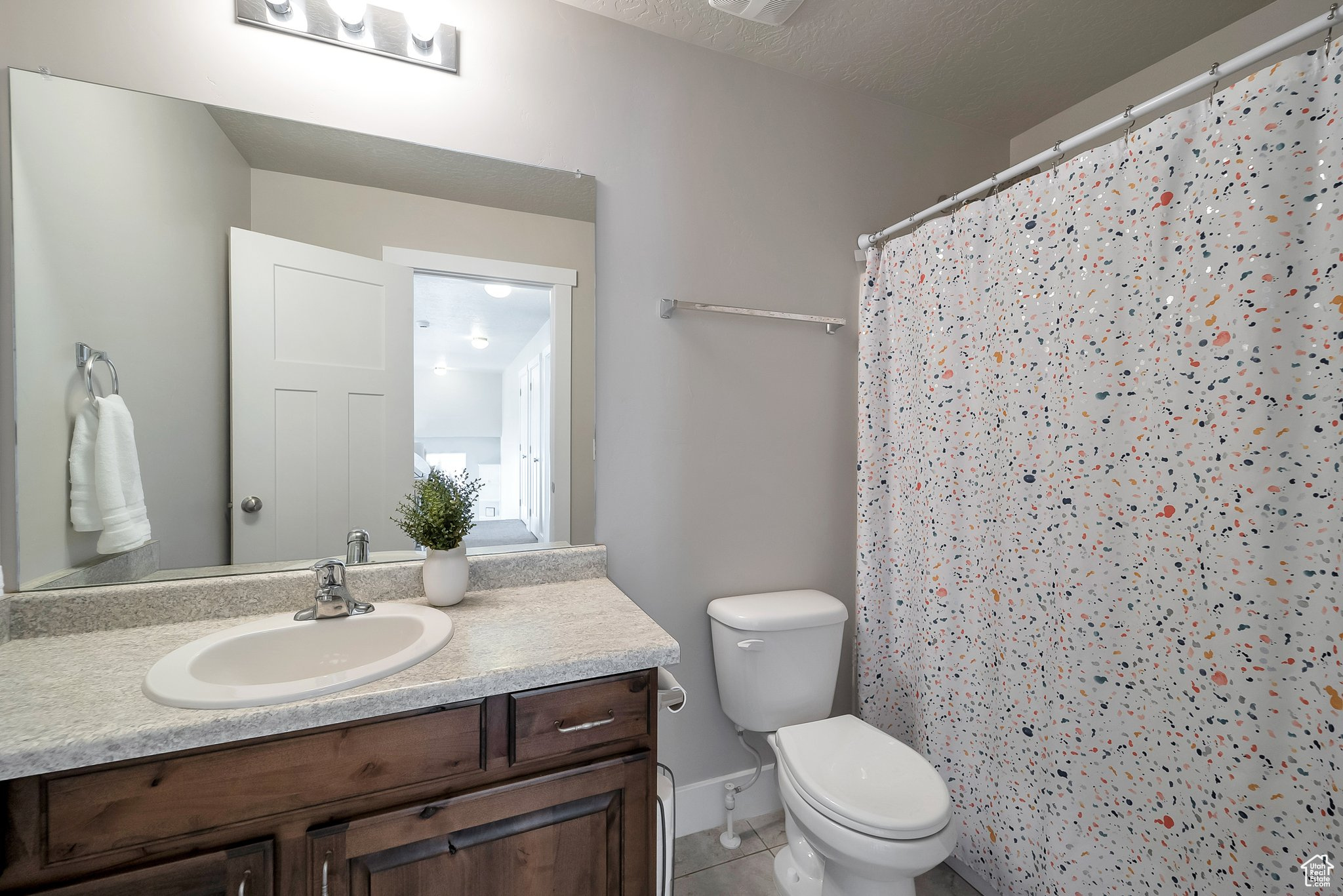 Bathroom with vanity, tile patterned floors, toilet, and a shower with shower curtain