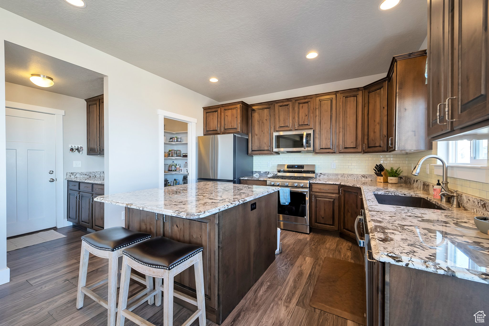 Kitchen featuring a sink, a kitchen island, appliances with stainless steel finishes, and dark wood finished floors