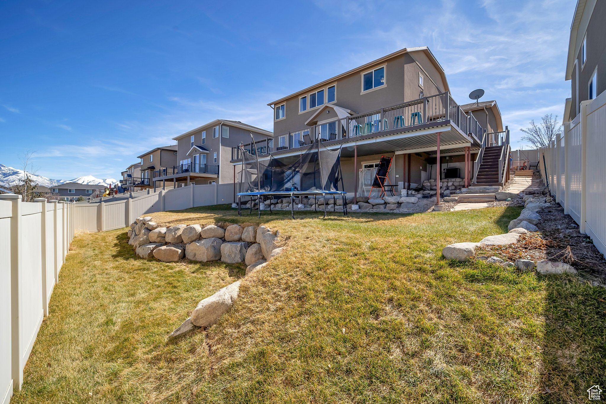 Rear view of property featuring stairs, a yard, a fenced backyard, and a trampoline