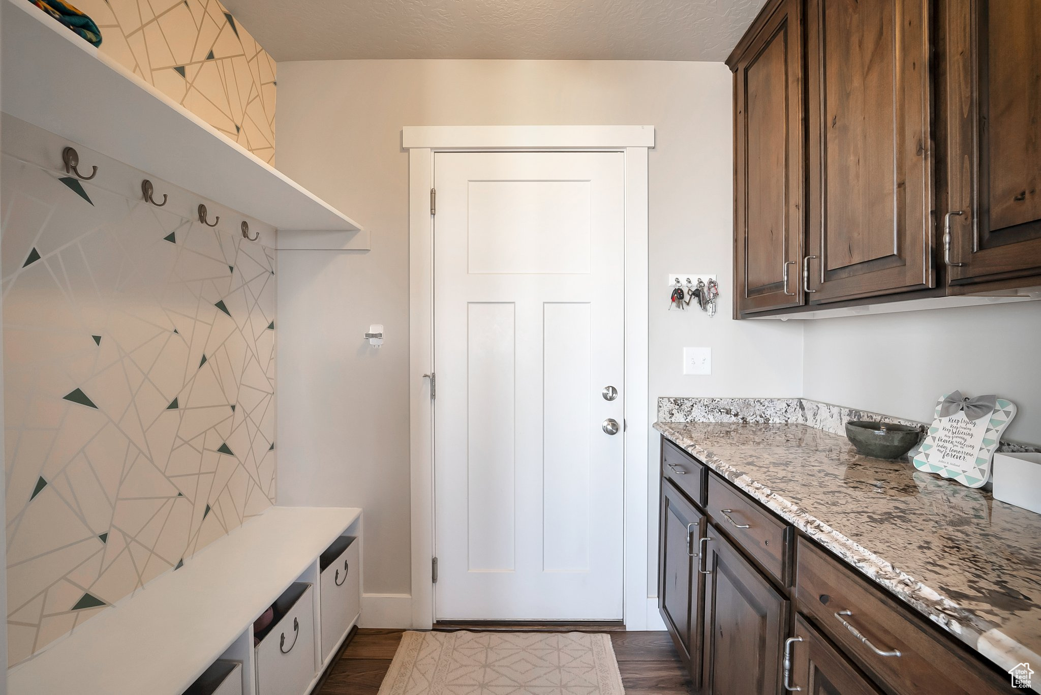 Mudroom featuring a textured ceiling and dark wood-style floors