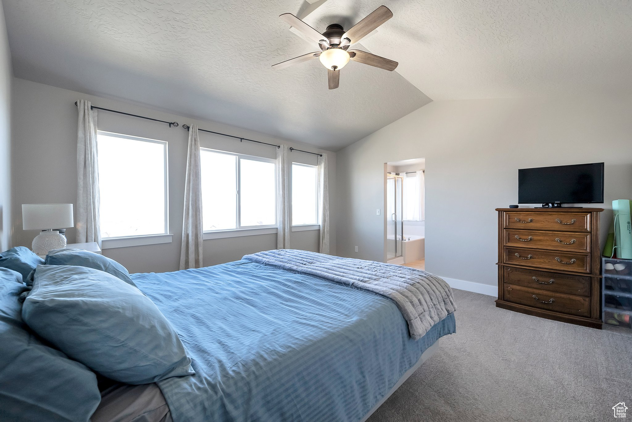 Bedroom featuring baseboards, ceiling fan, vaulted ceiling, a textured ceiling, and carpet flooring