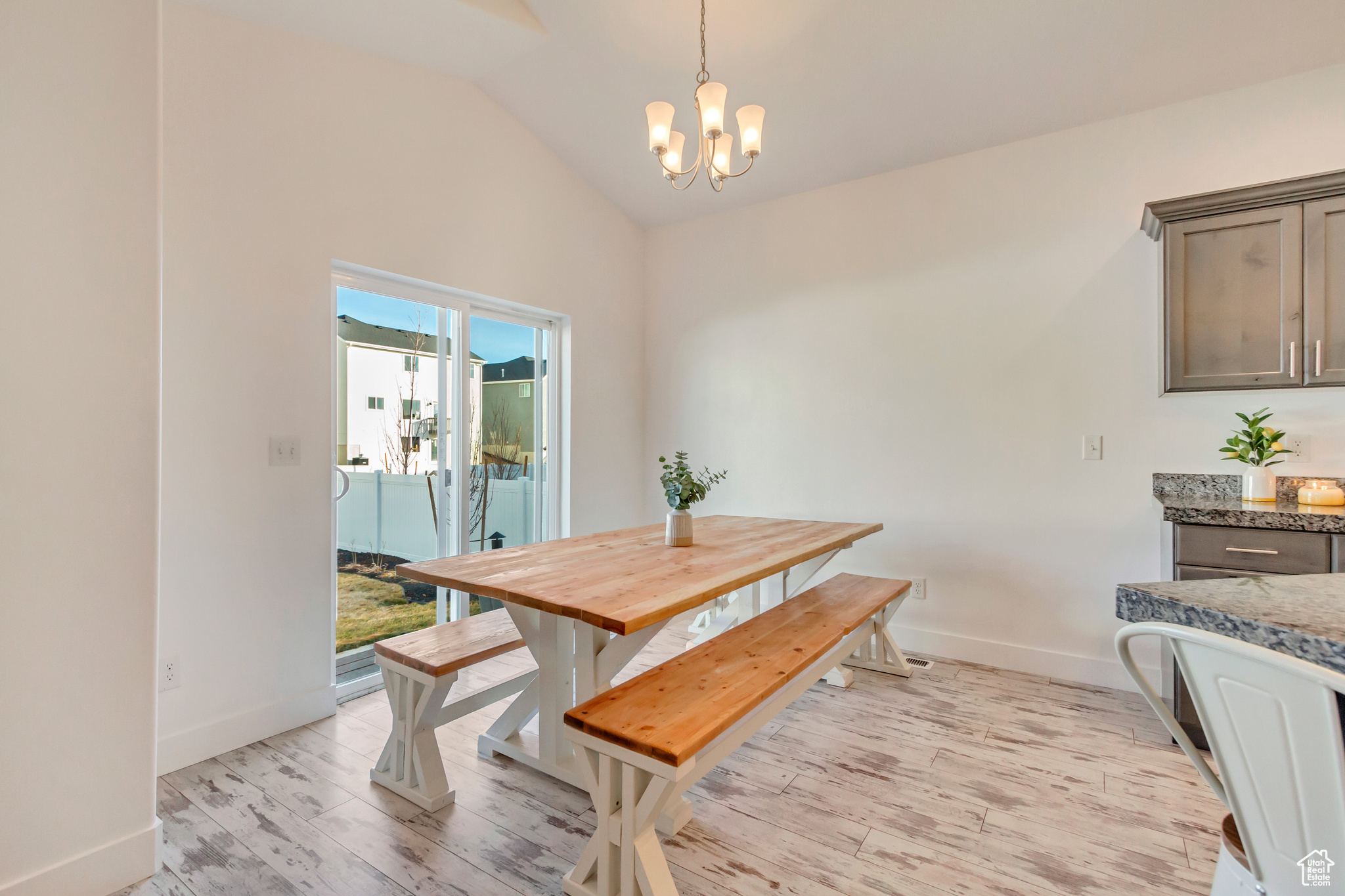 Dining room with vaulted ceiling, light wood-style flooring, baseboards, and a chandelier