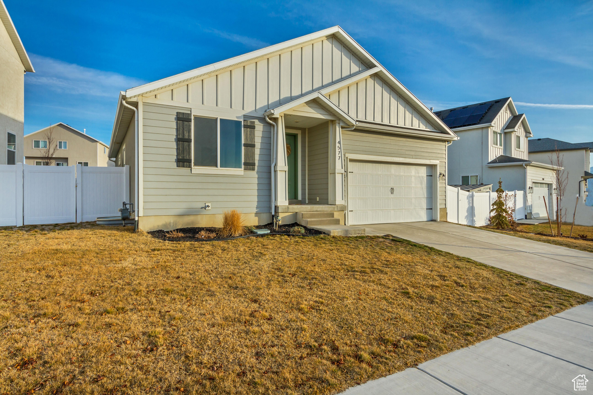 View of front of property featuring board and batten siding, concrete driveway, a garage, and fence