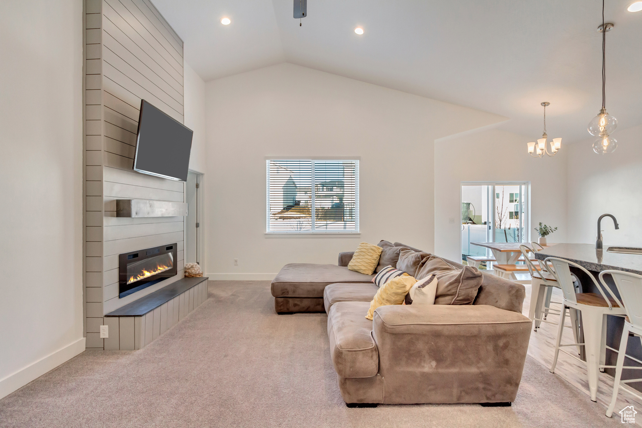 Living area featuring a fireplace, baseboards, carpet floors, and high vaulted ceiling