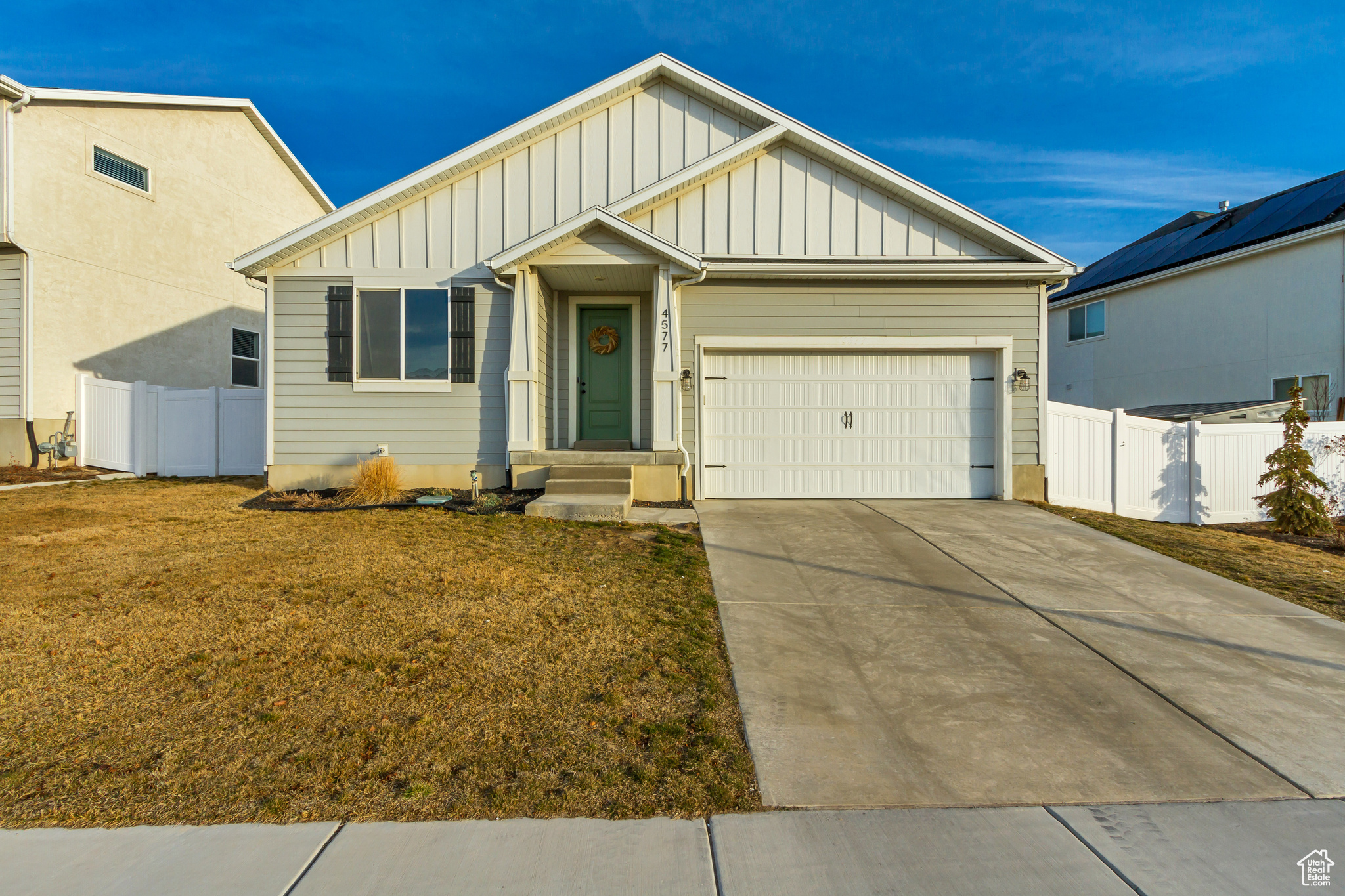 View of front of property featuring board and batten siding, an attached garage, and fence