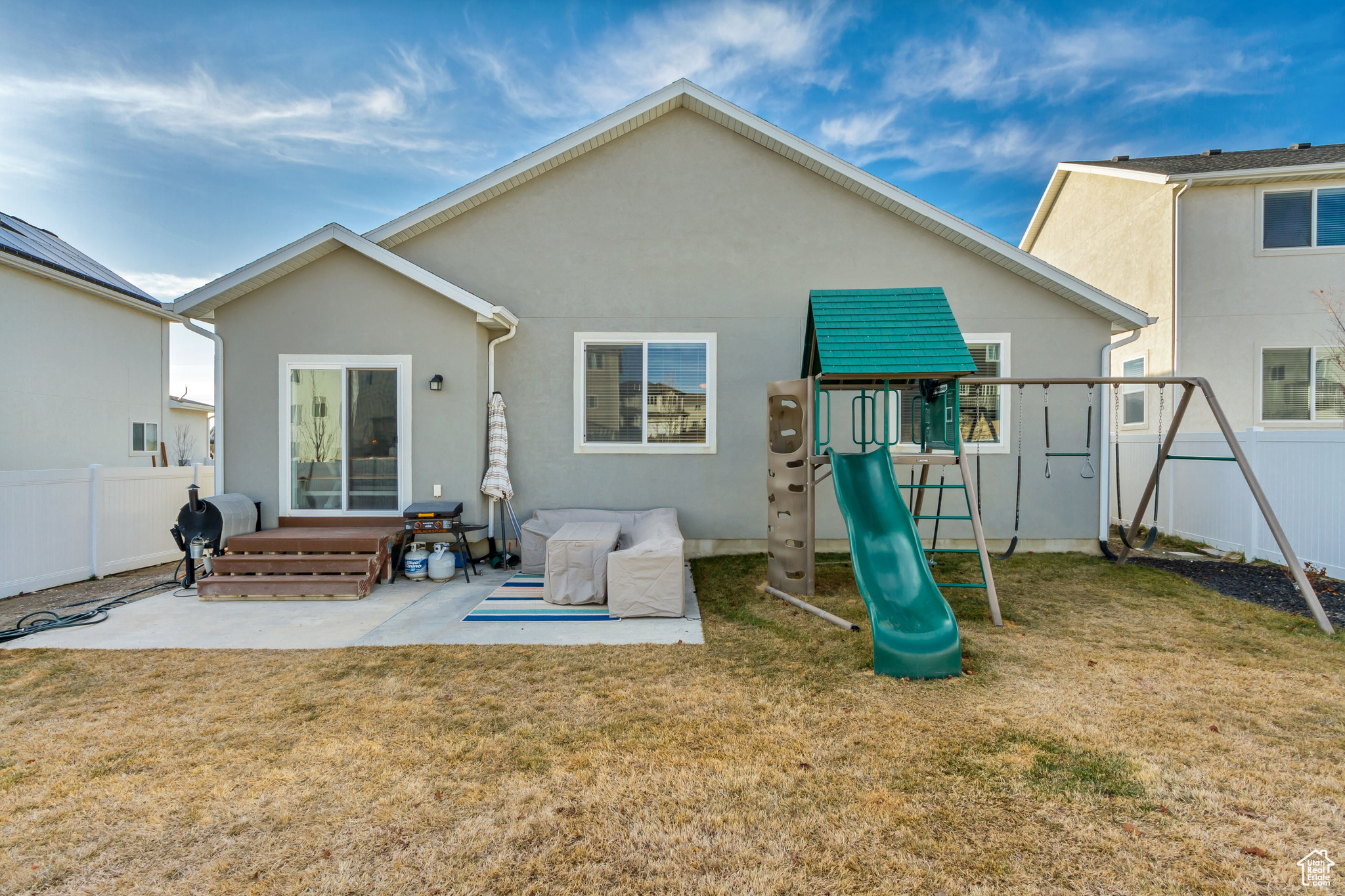Back of property with stucco siding, a patio, a yard, and fence