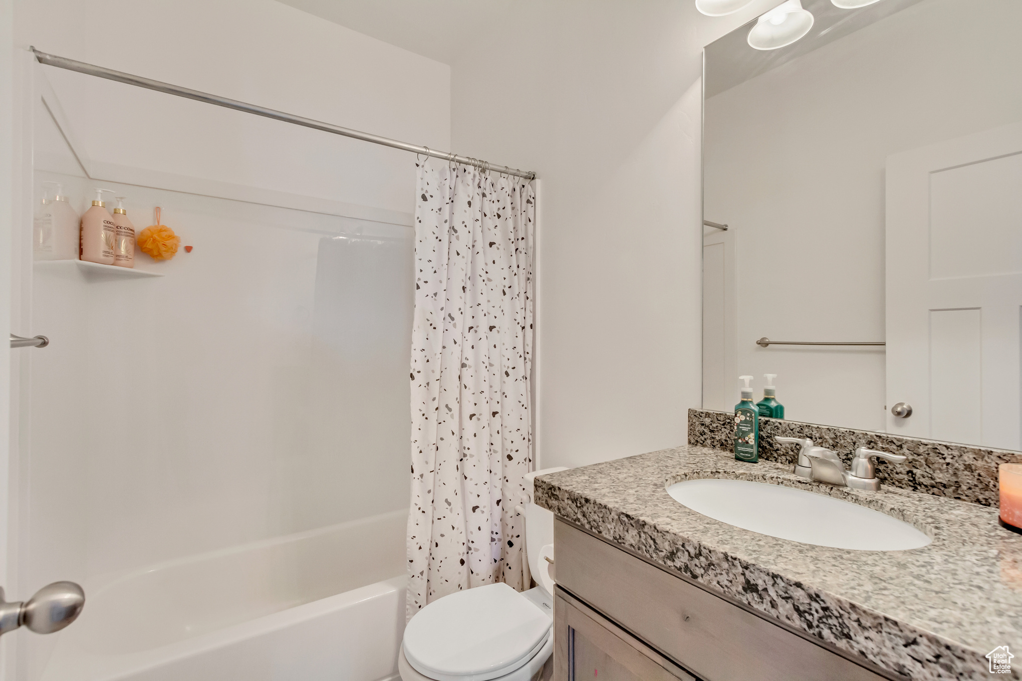 Bathroom with vanity, shower / bath combination with curtain, and toilet