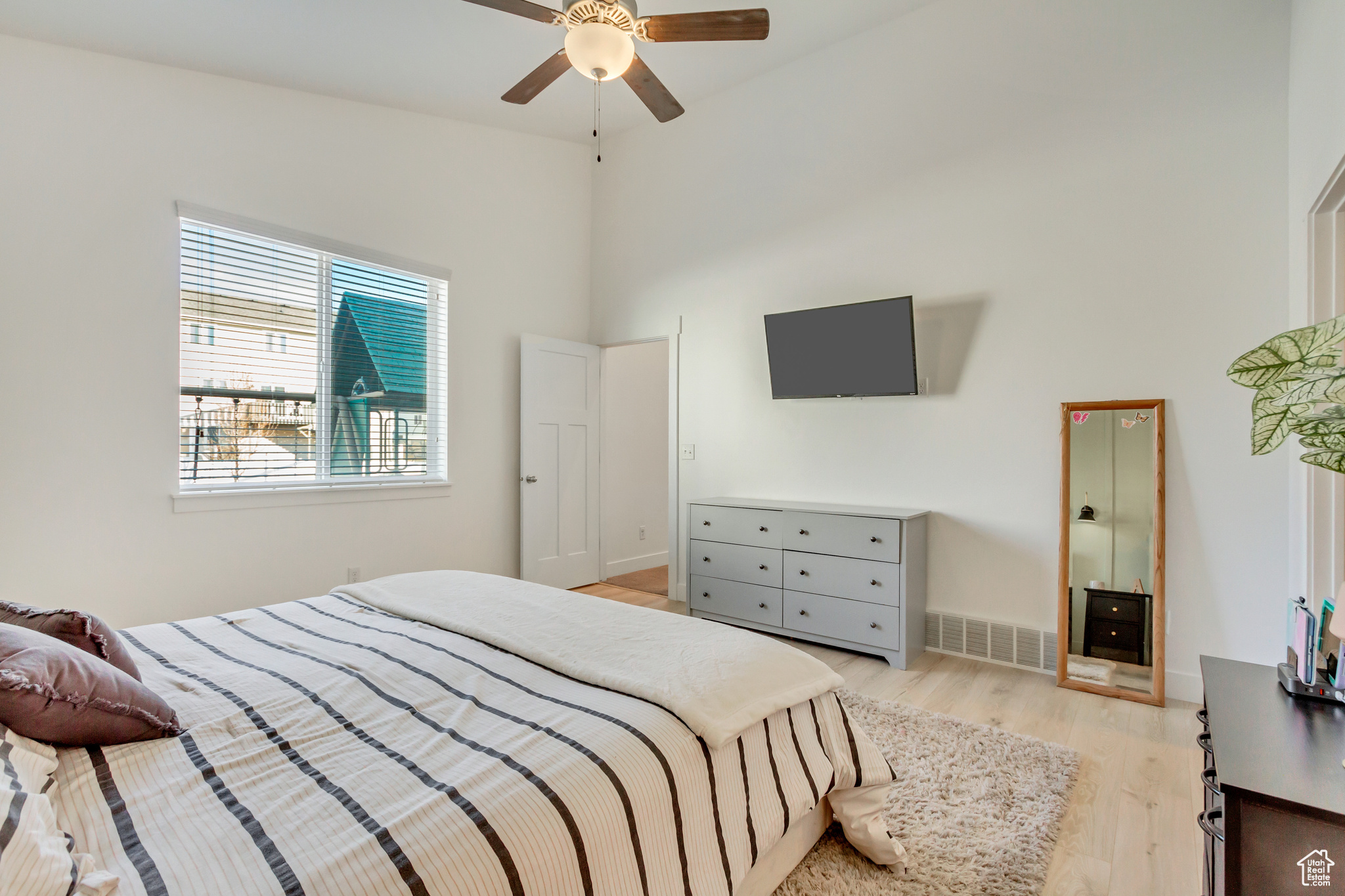 Bedroom featuring visible vents, ceiling fan, a high ceiling, and light wood-style floors