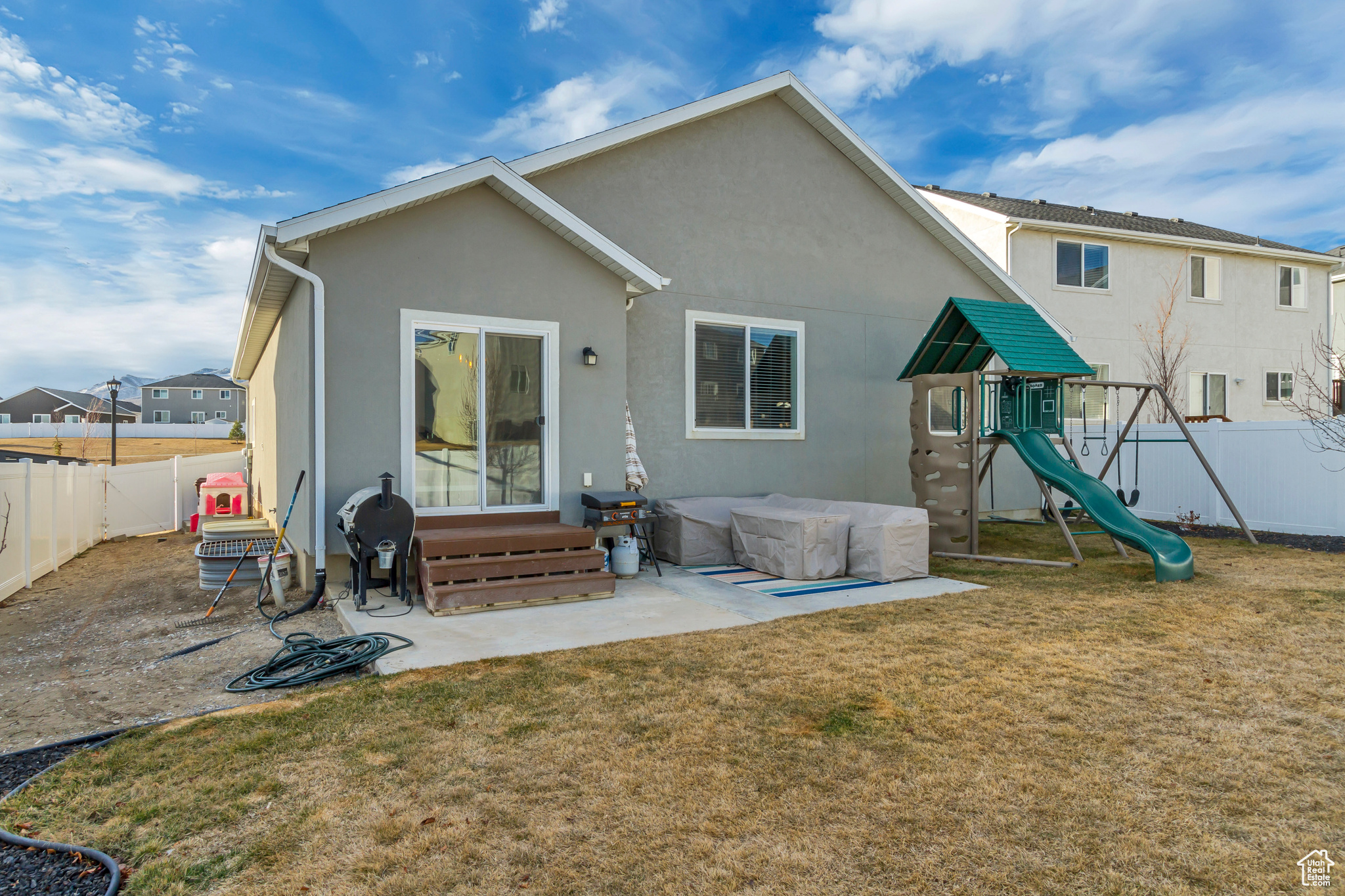 Rear view of property with entry steps, a playground, a fenced backyard, and a lawn