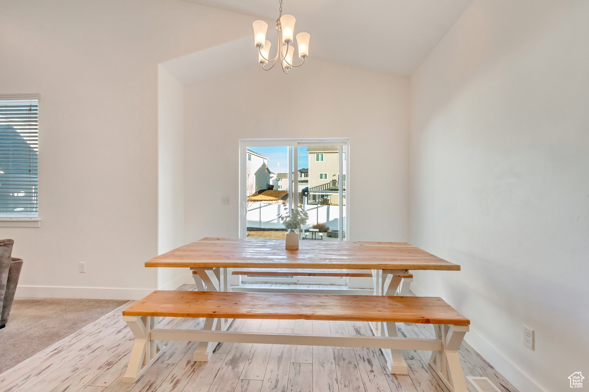 Dining space with an inviting chandelier, vaulted ceiling, wood finished floors, and baseboards