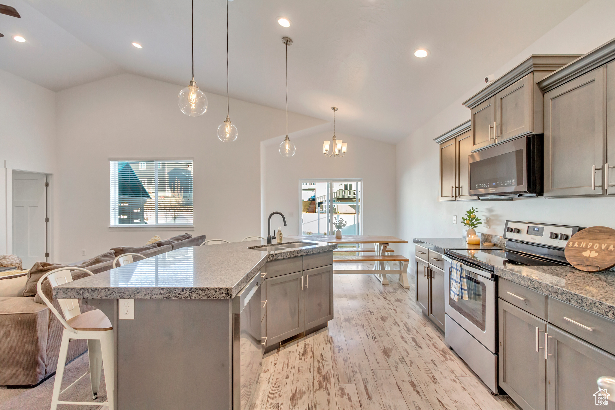 Kitchen featuring a breakfast bar area, vaulted ceiling, appliances with stainless steel finishes, light wood-style floors, and a sink