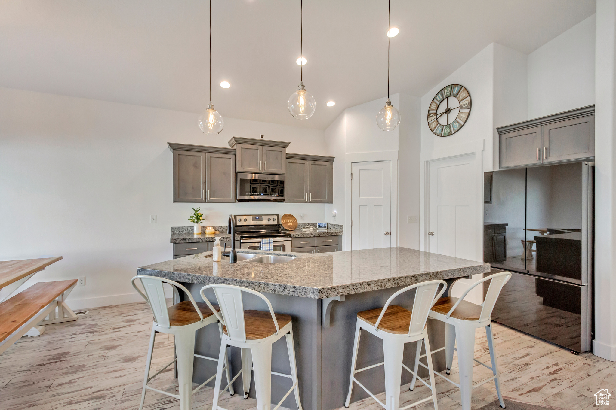 Kitchen with a sink, light wood-type flooring, a kitchen bar, and appliances with stainless steel finishes