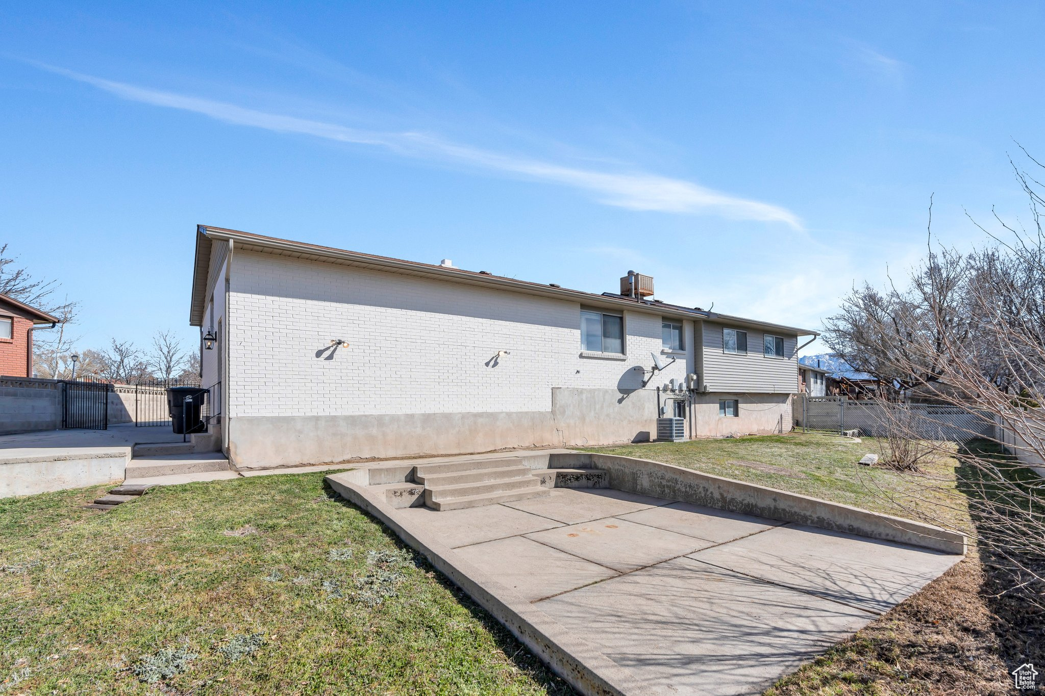 Rear view of house with a patio, fence, a lawn, and brick siding