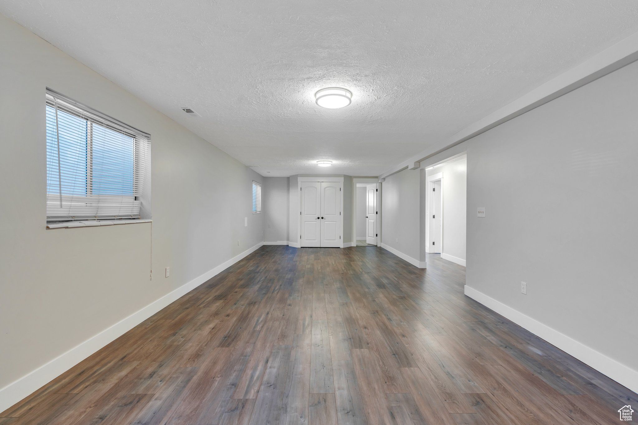 Spare room with baseboards, a textured ceiling, and dark wood-style flooring