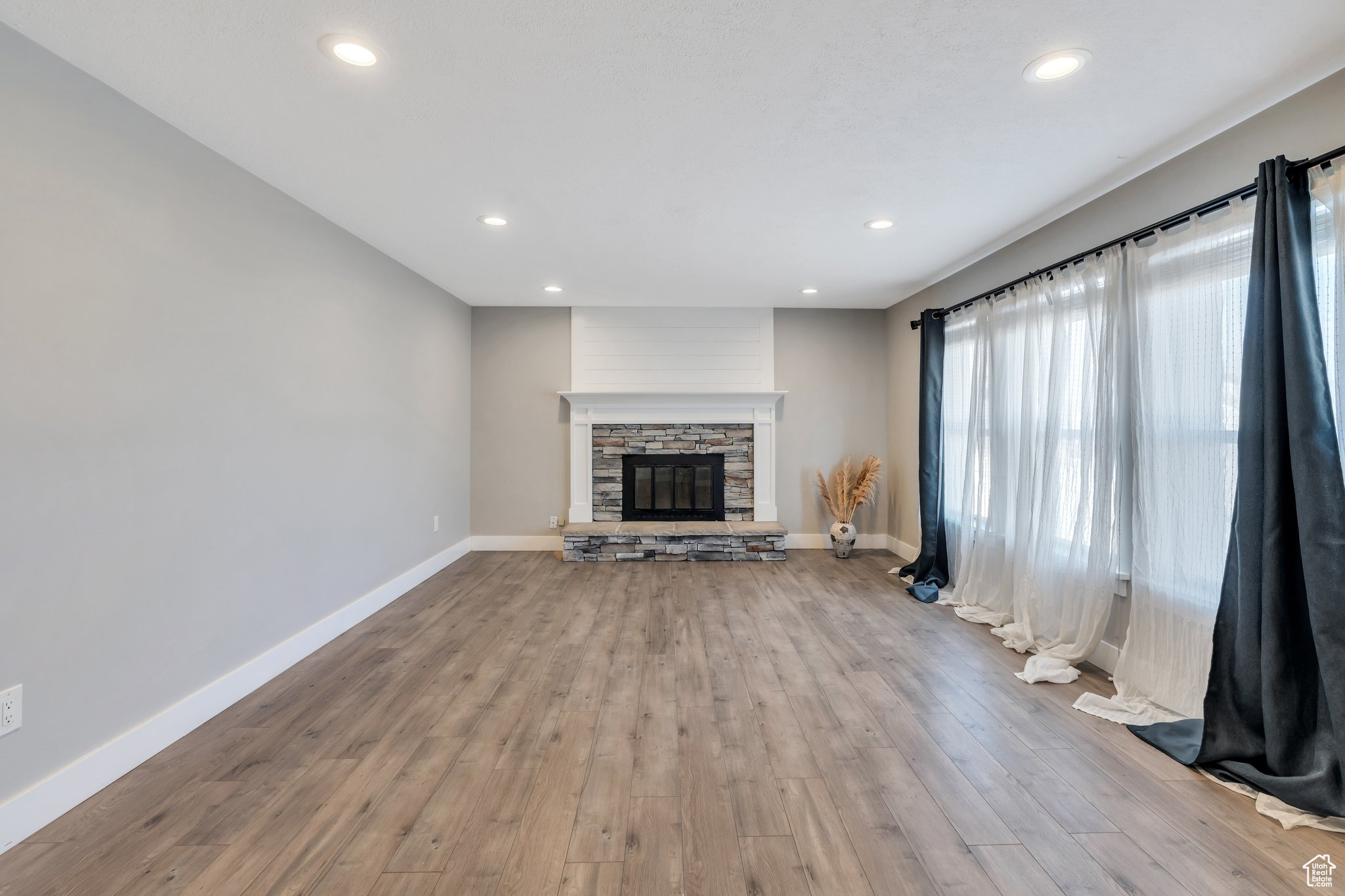 Unfurnished living room with a fireplace, recessed lighting, wood finished floors, and baseboards