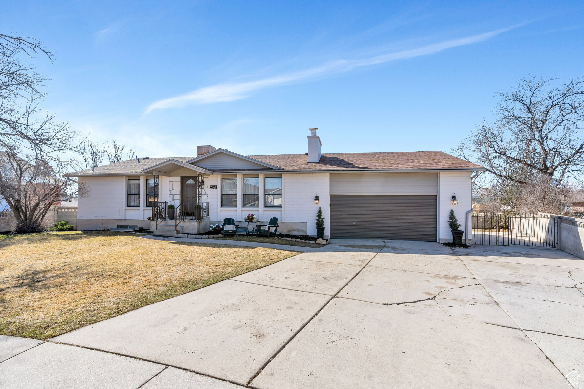 View of front of property with a gate, fence, concrete driveway, a front yard, and a garage