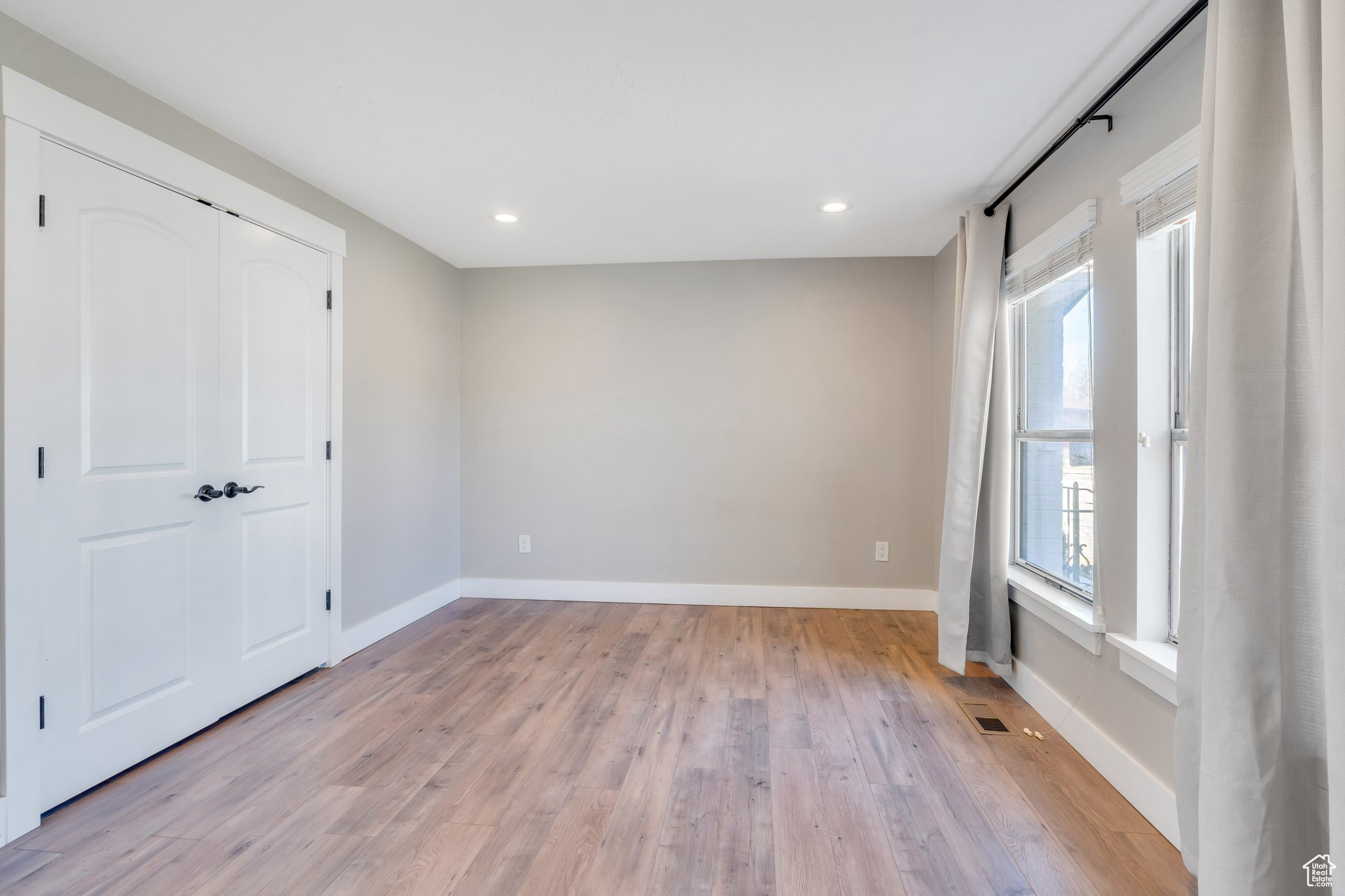 Empty room featuring visible vents, light wood-style flooring, recessed lighting, and baseboards