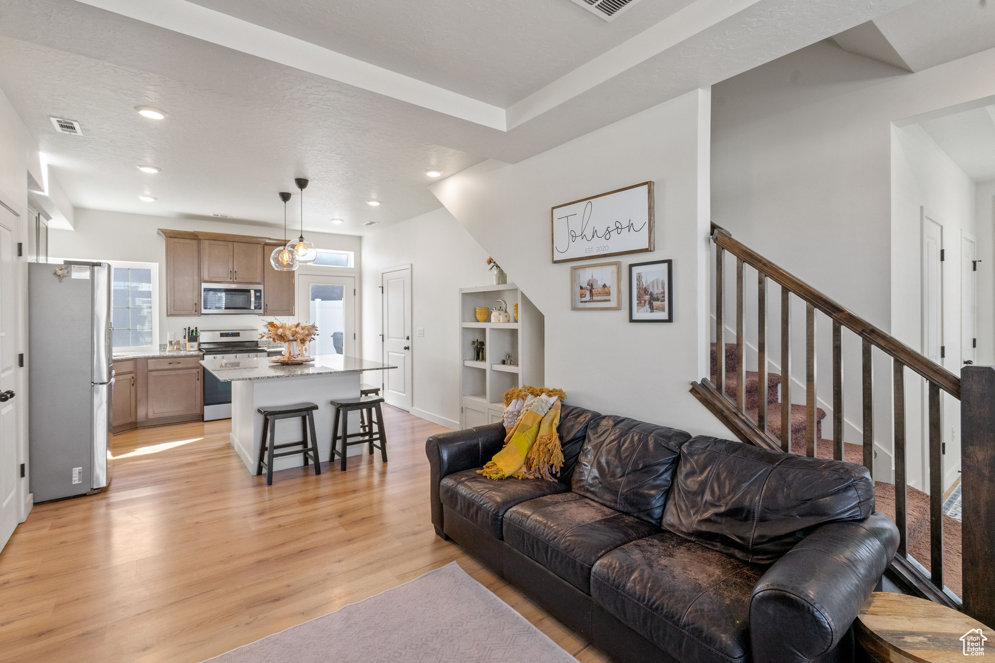 Living room with light wood finished floors, visible vents, recessed lighting, and stairs