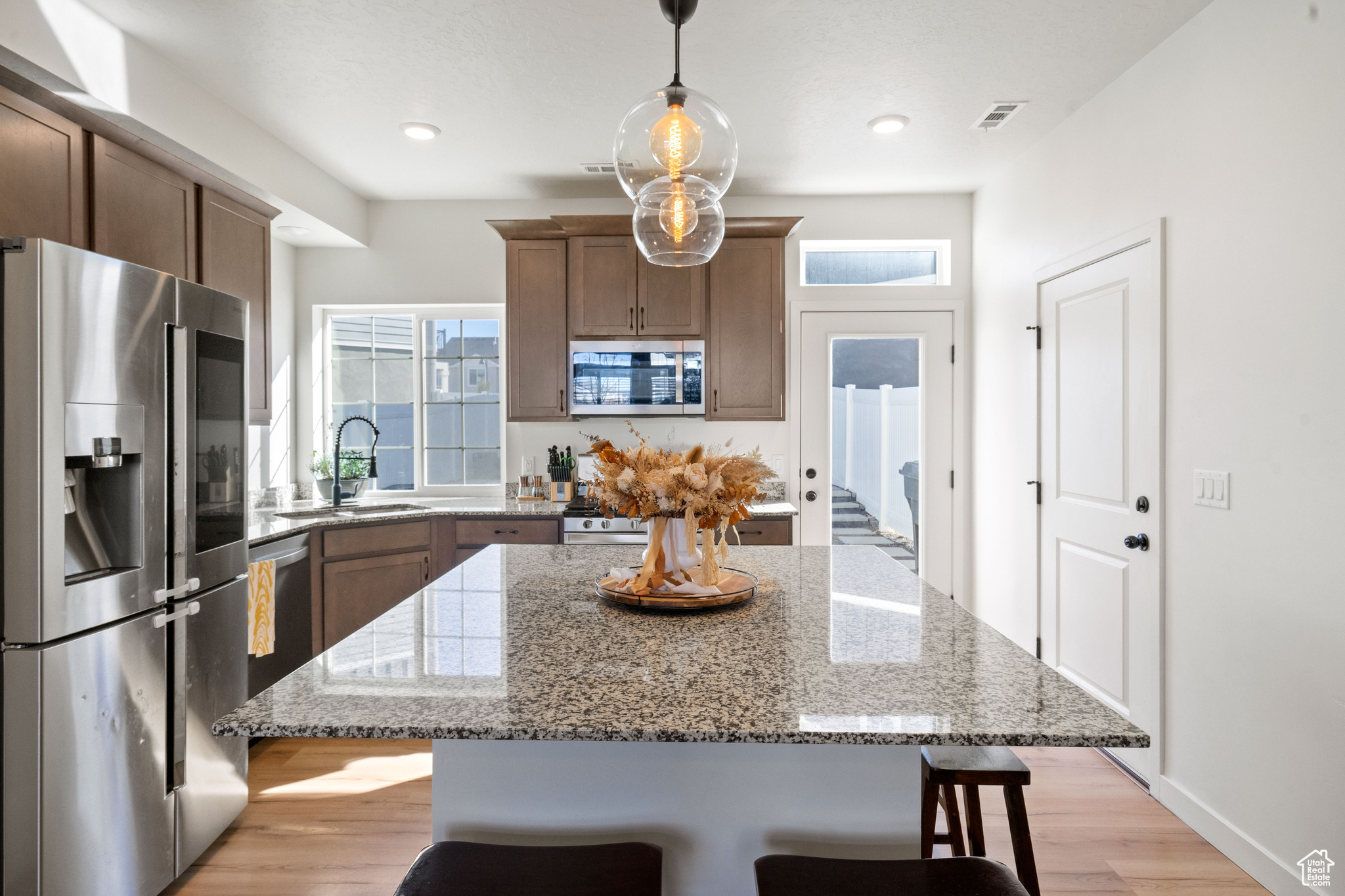 Kitchen with a breakfast bar, light wood-style floors, a kitchen island, and stainless steel appliances