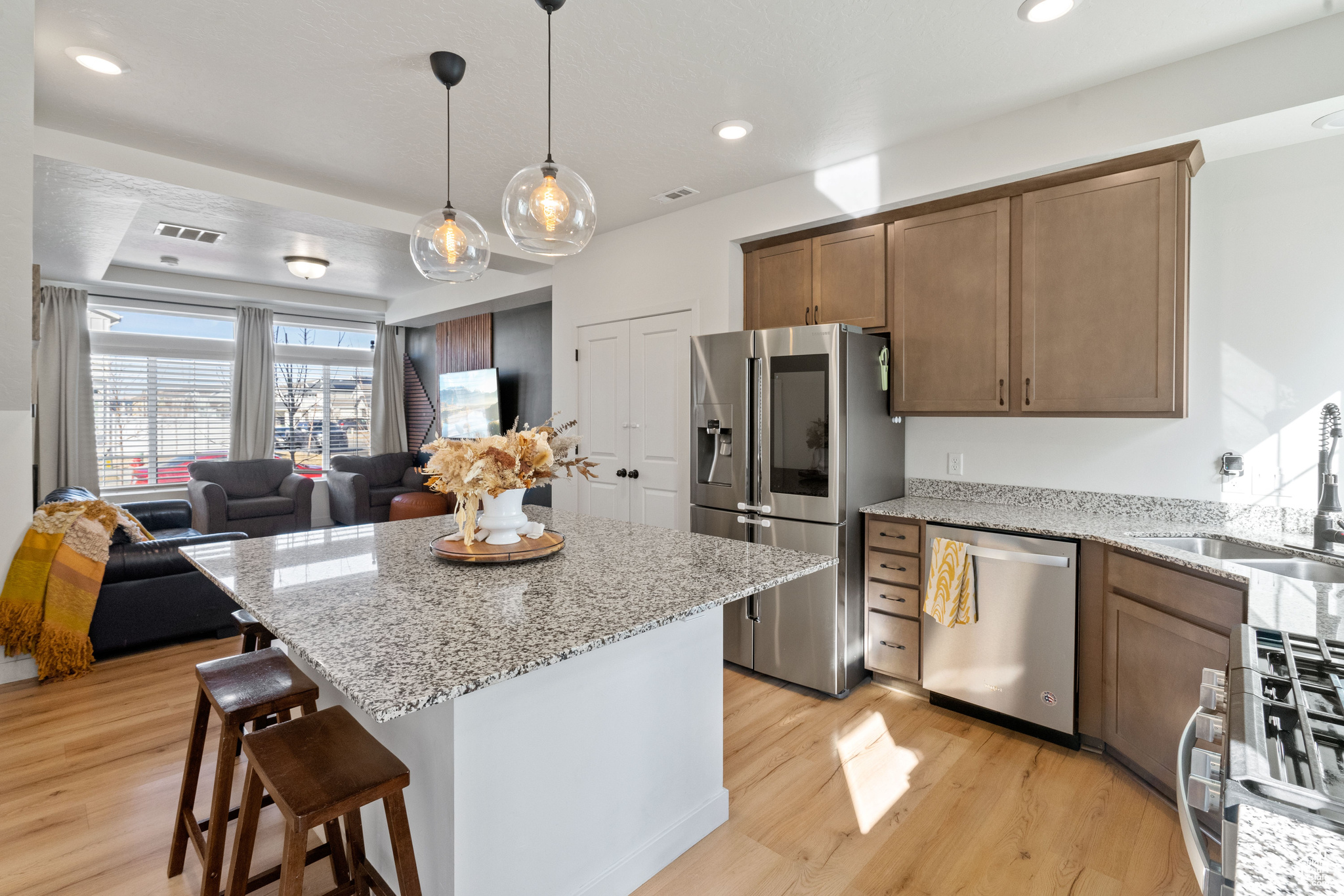 Kitchen featuring visible vents, open floor plan, appliances with stainless steel finishes, light wood-style floors, and a sink