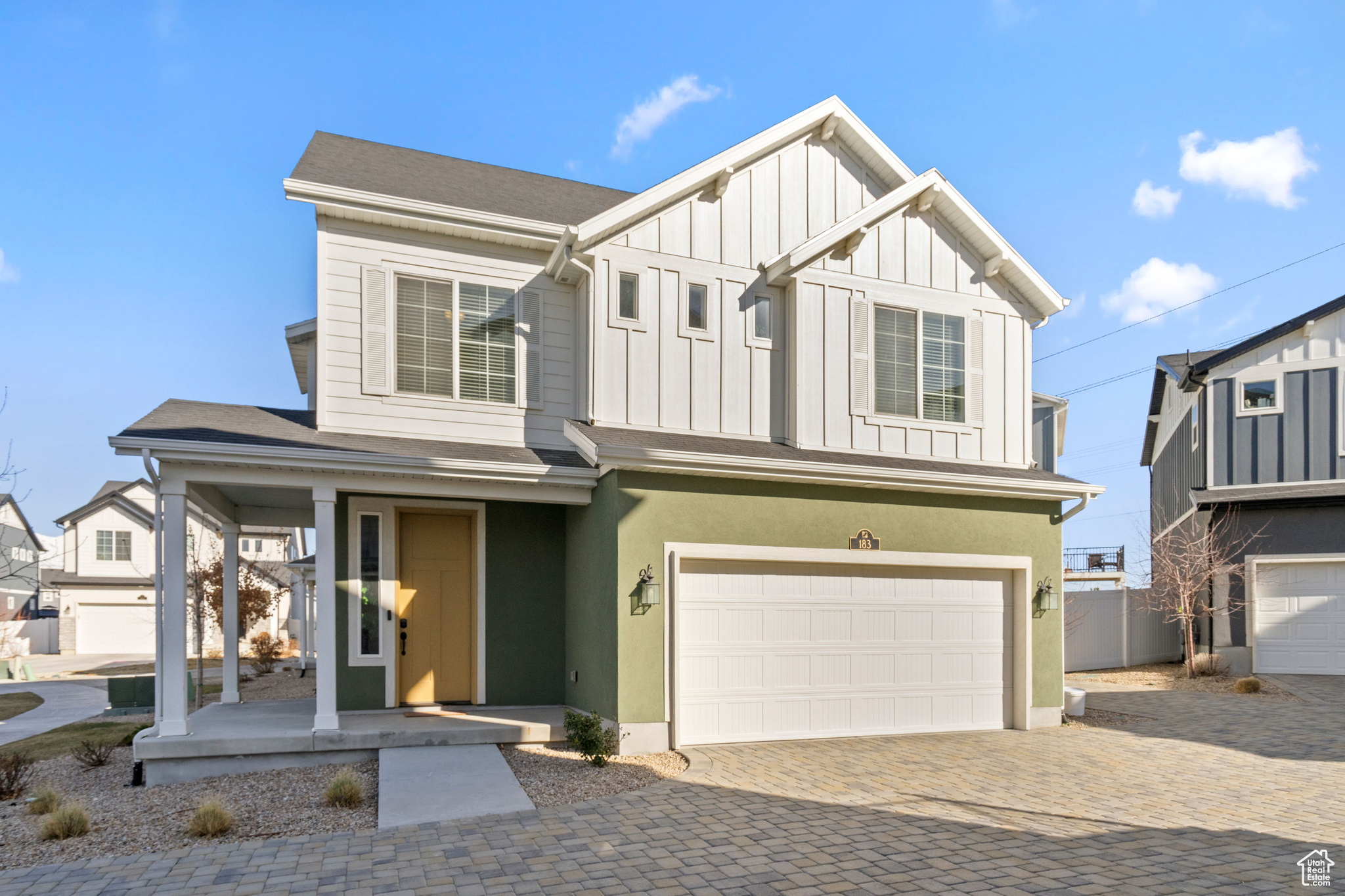 View of front of property with stucco siding, decorative driveway, covered porch, board and batten siding, and a garage