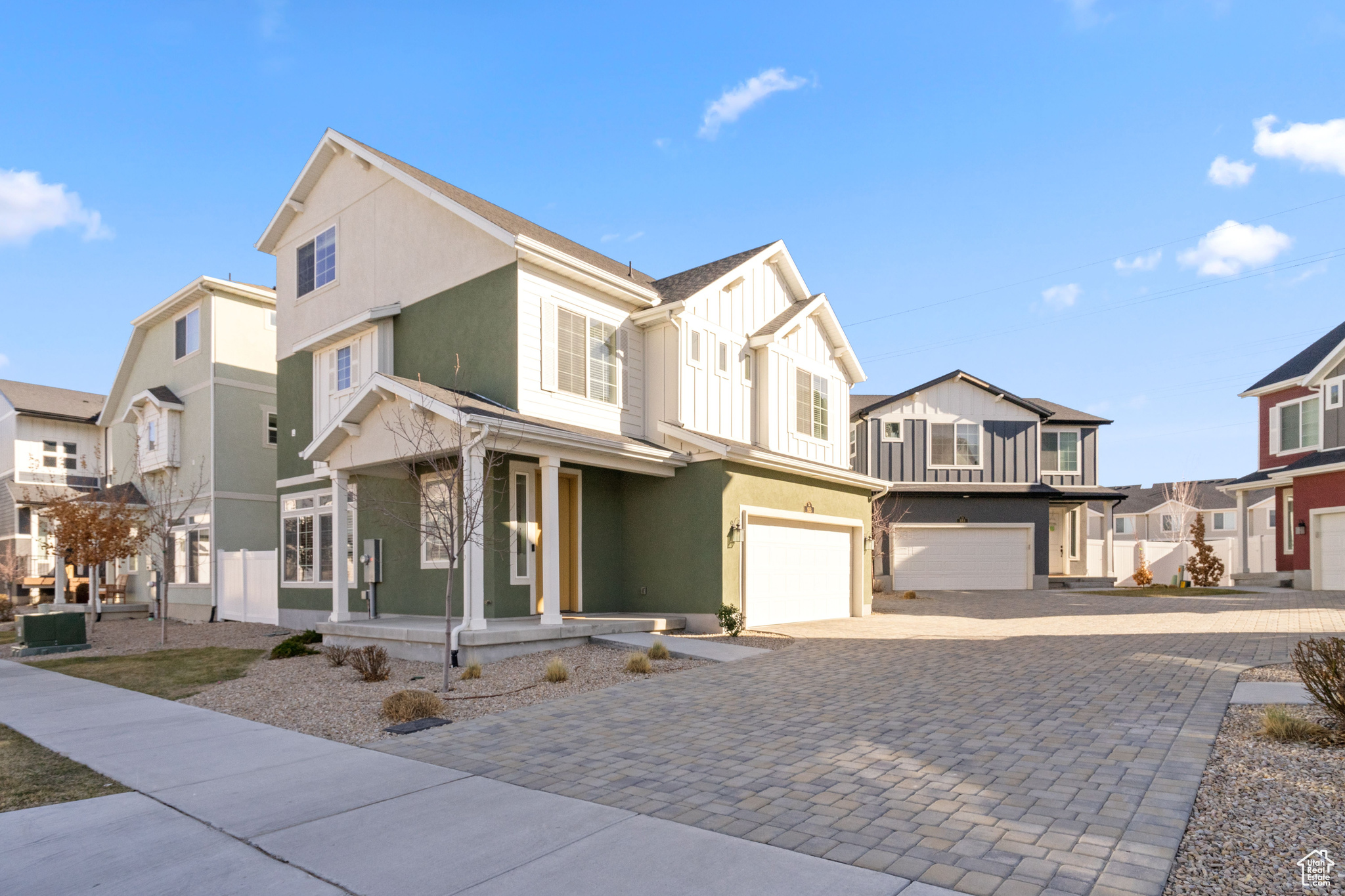 View of front of property featuring board and batten siding, a residential view, a porch, decorative driveway, and an attached garage