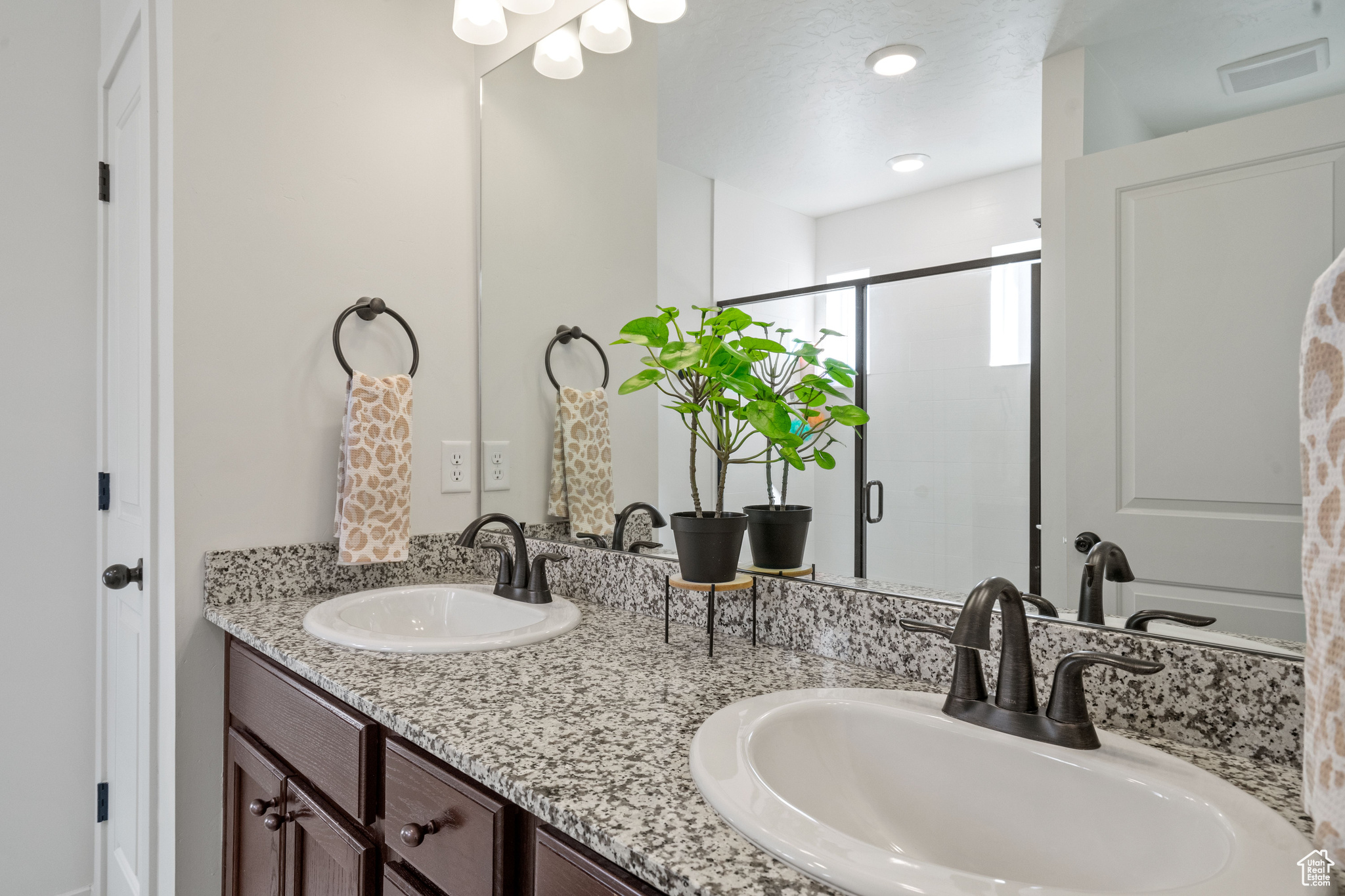 Bathroom featuring double vanity, visible vents, a stall shower, and a sink