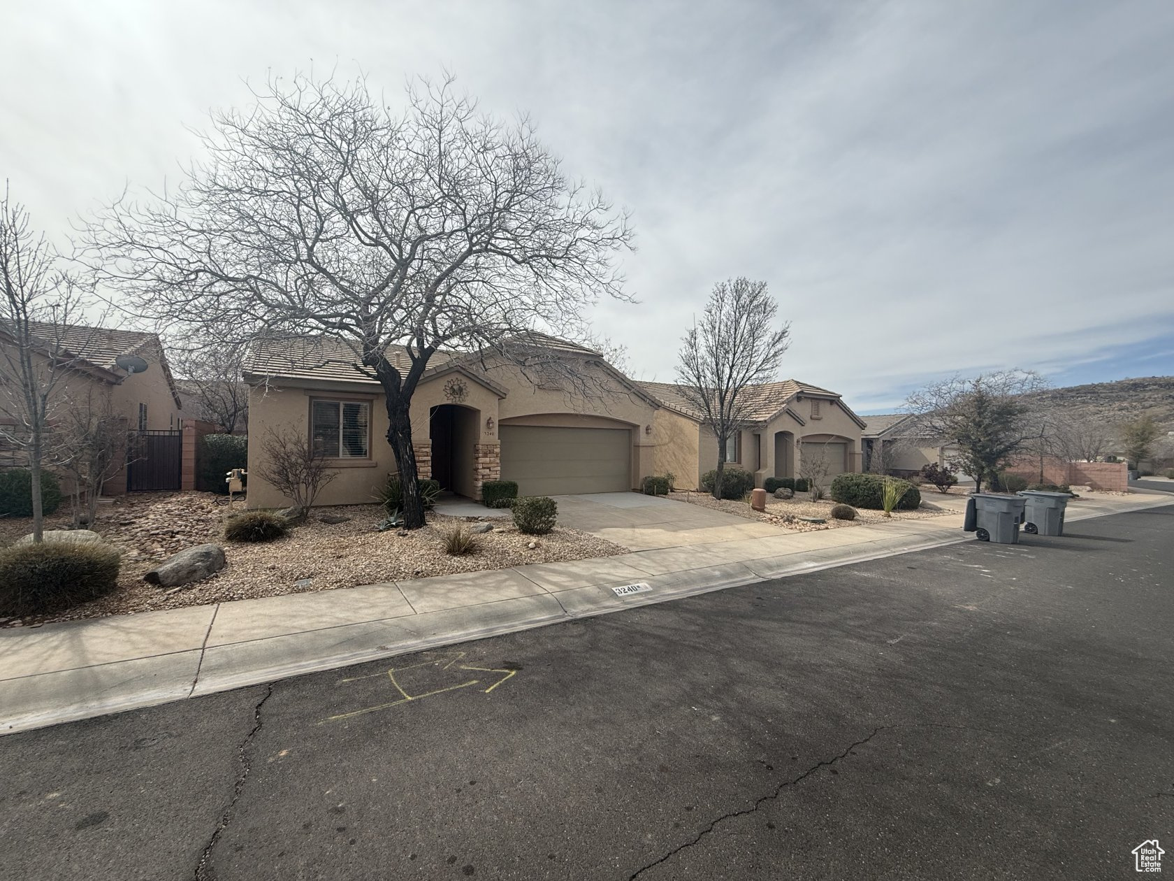 View of front of house with fence, a garage, driveway, and stucco siding
