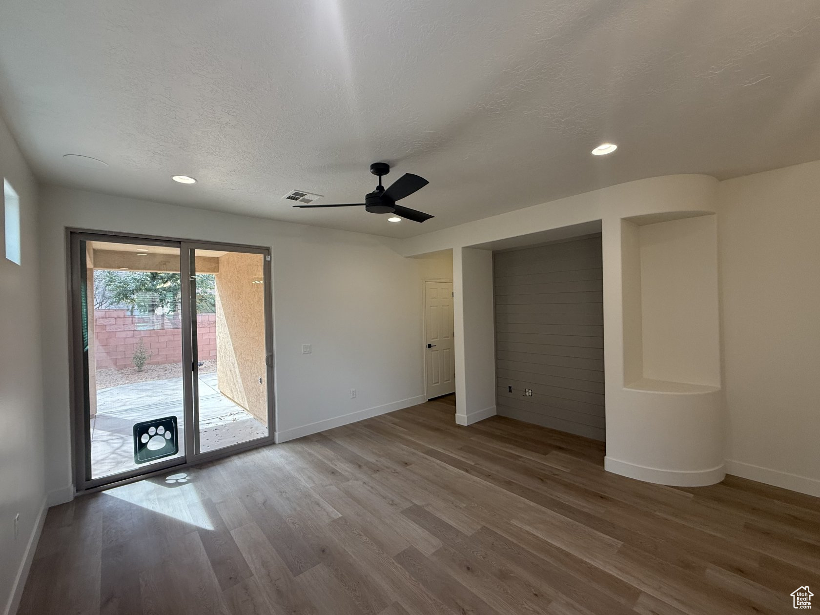 Unfurnished bedroom featuring baseboards, a textured ceiling, wood finished floors, and access to outside
